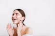 A woman in a white dress smiling and touching her face