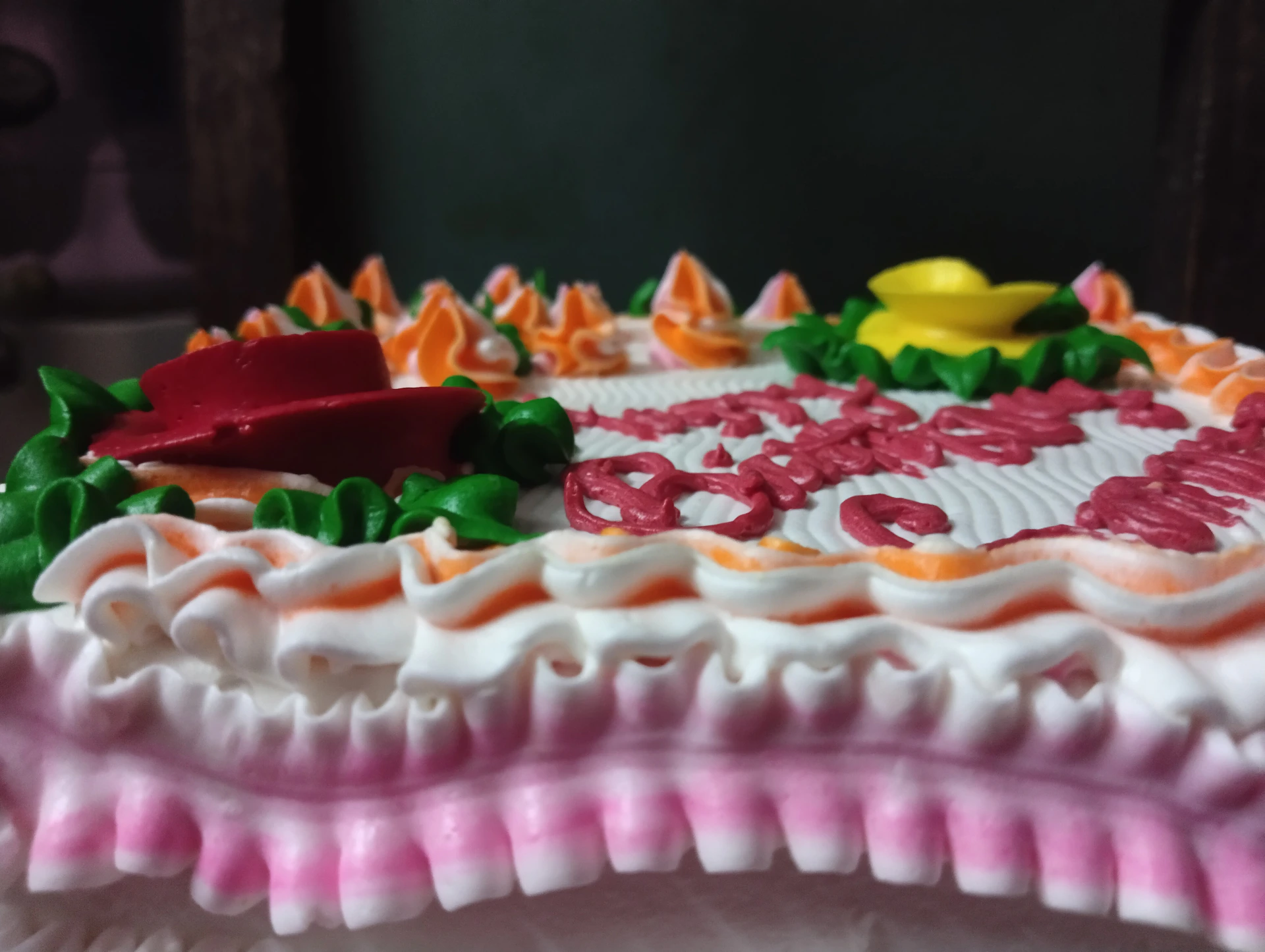 A cake with pink and white frosting and a yellow and yellow bird on top