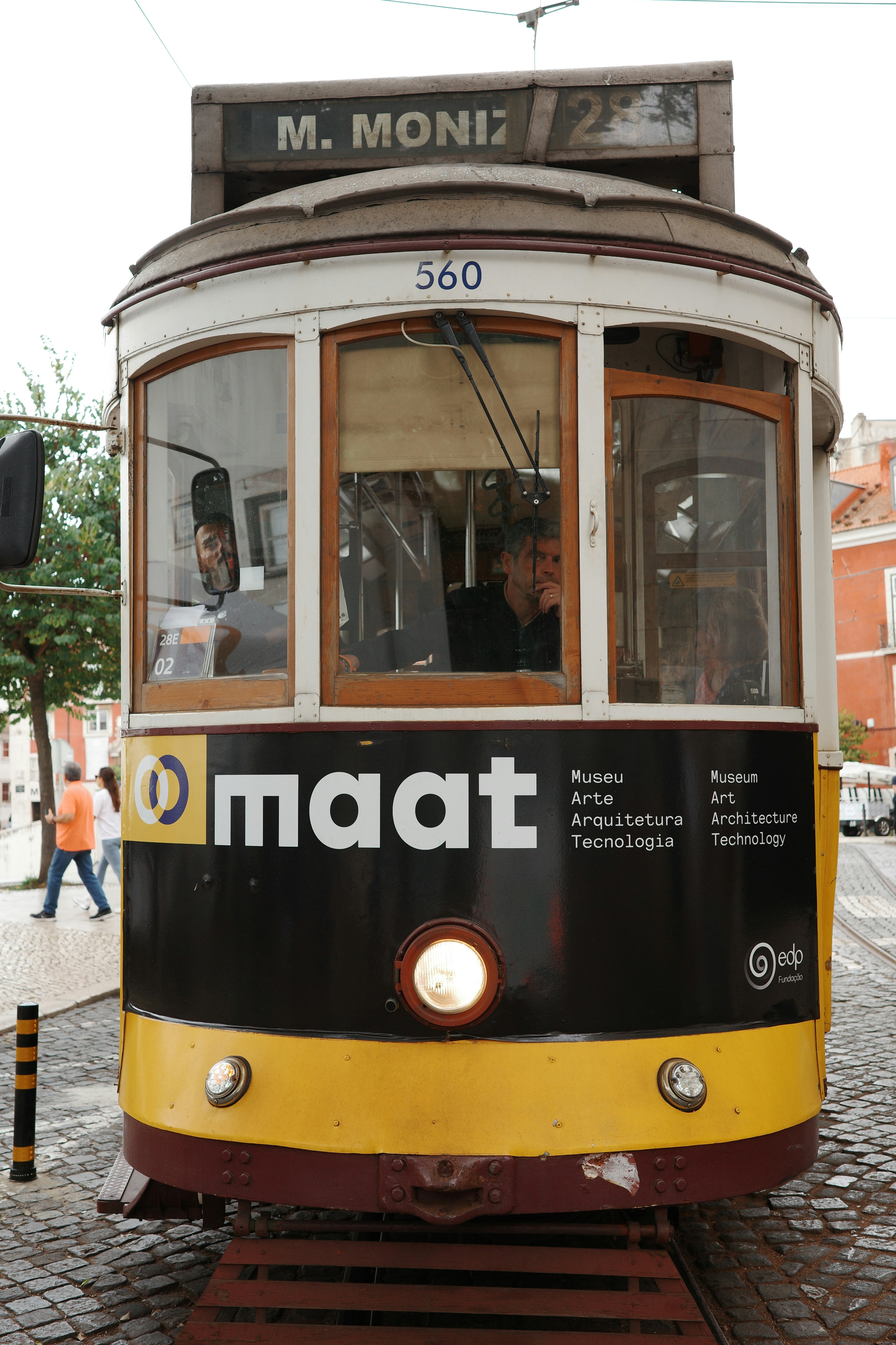 A yellow and black tram car on a street