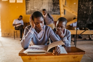 A couple of kids that are sitting in a desk