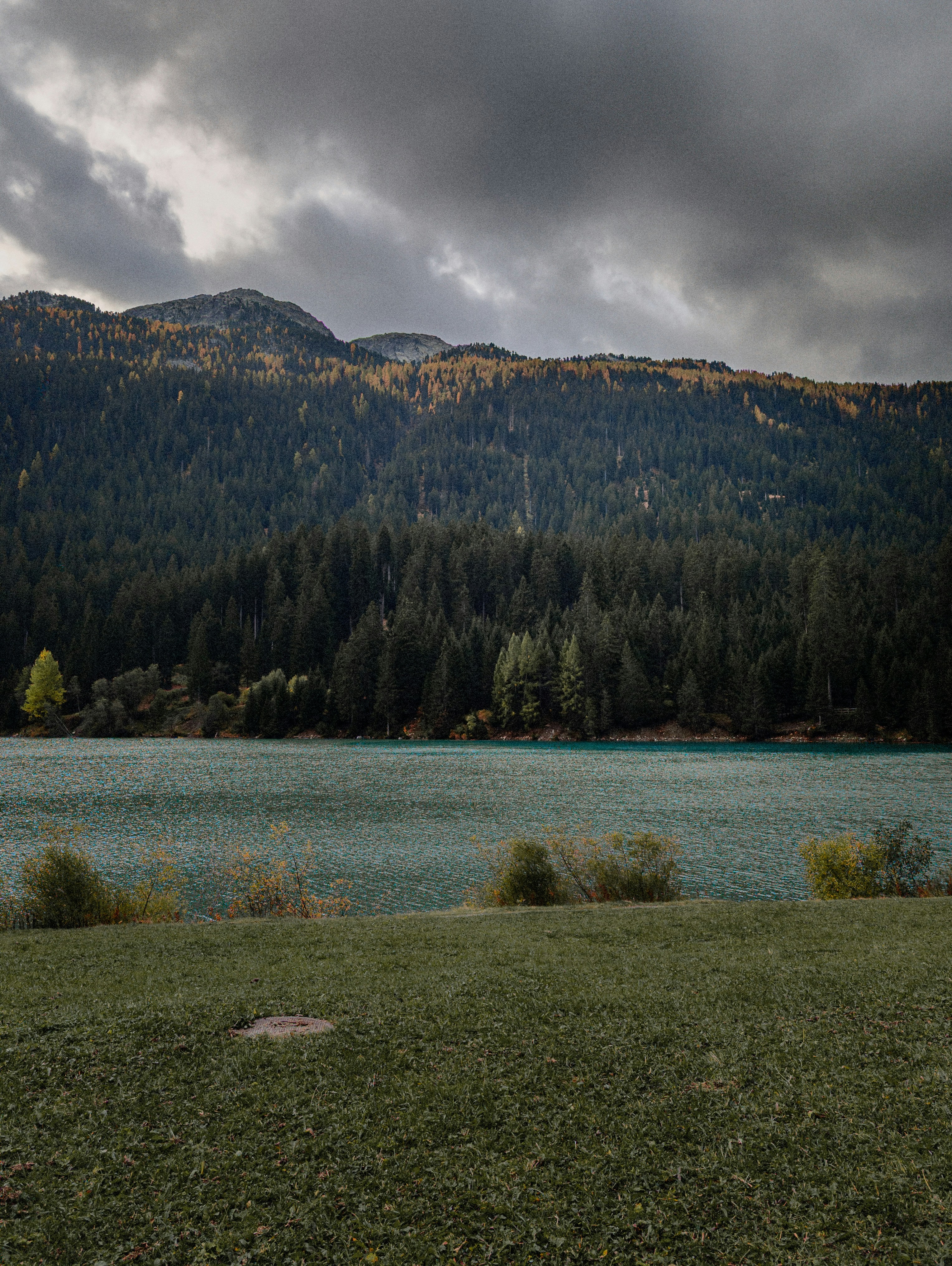 Un homme debout devant un lac sous un ciel nuageux