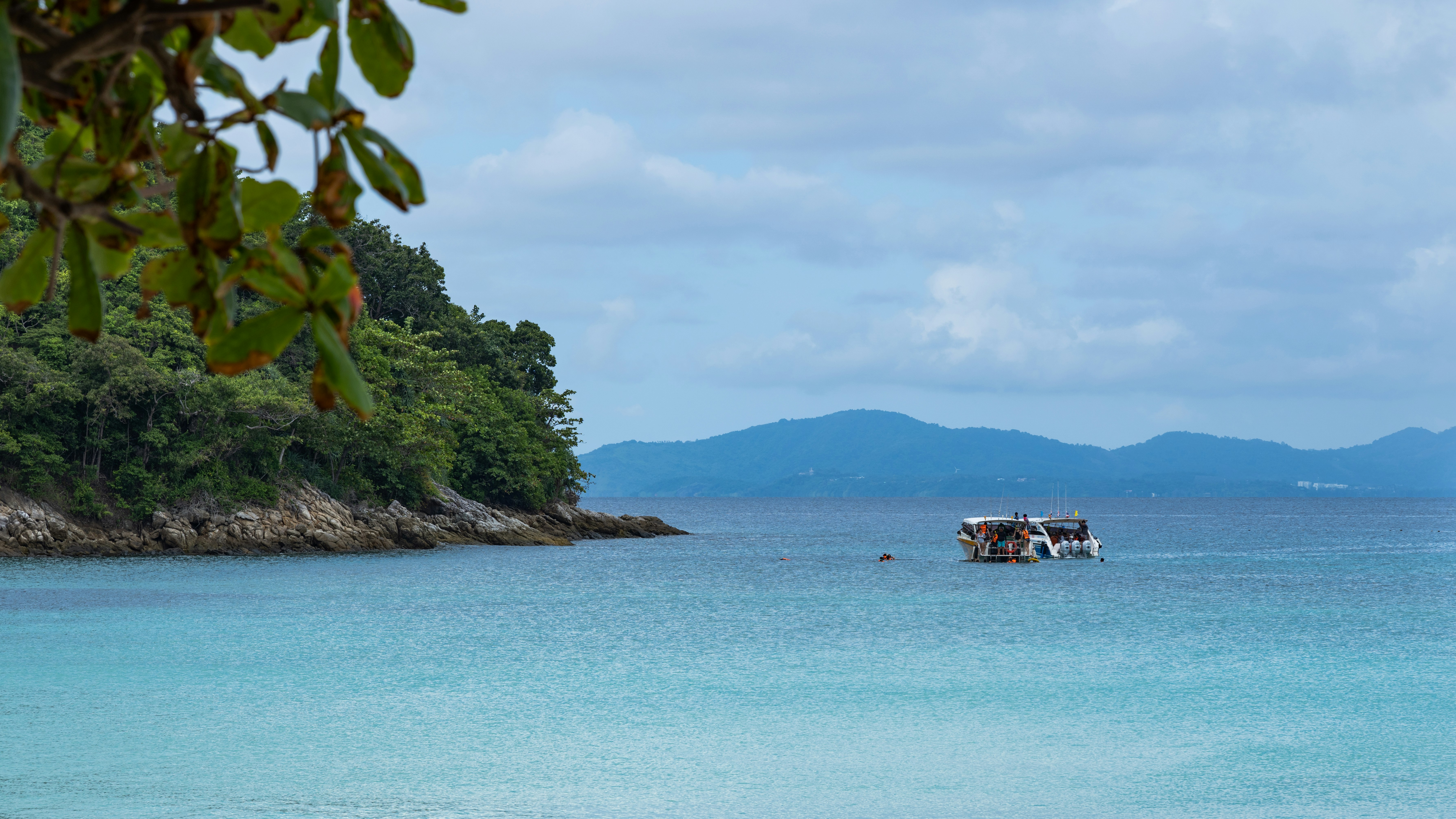 Happy tourists on a small boat feeding swimming pigs in clear turquoise shallow water
