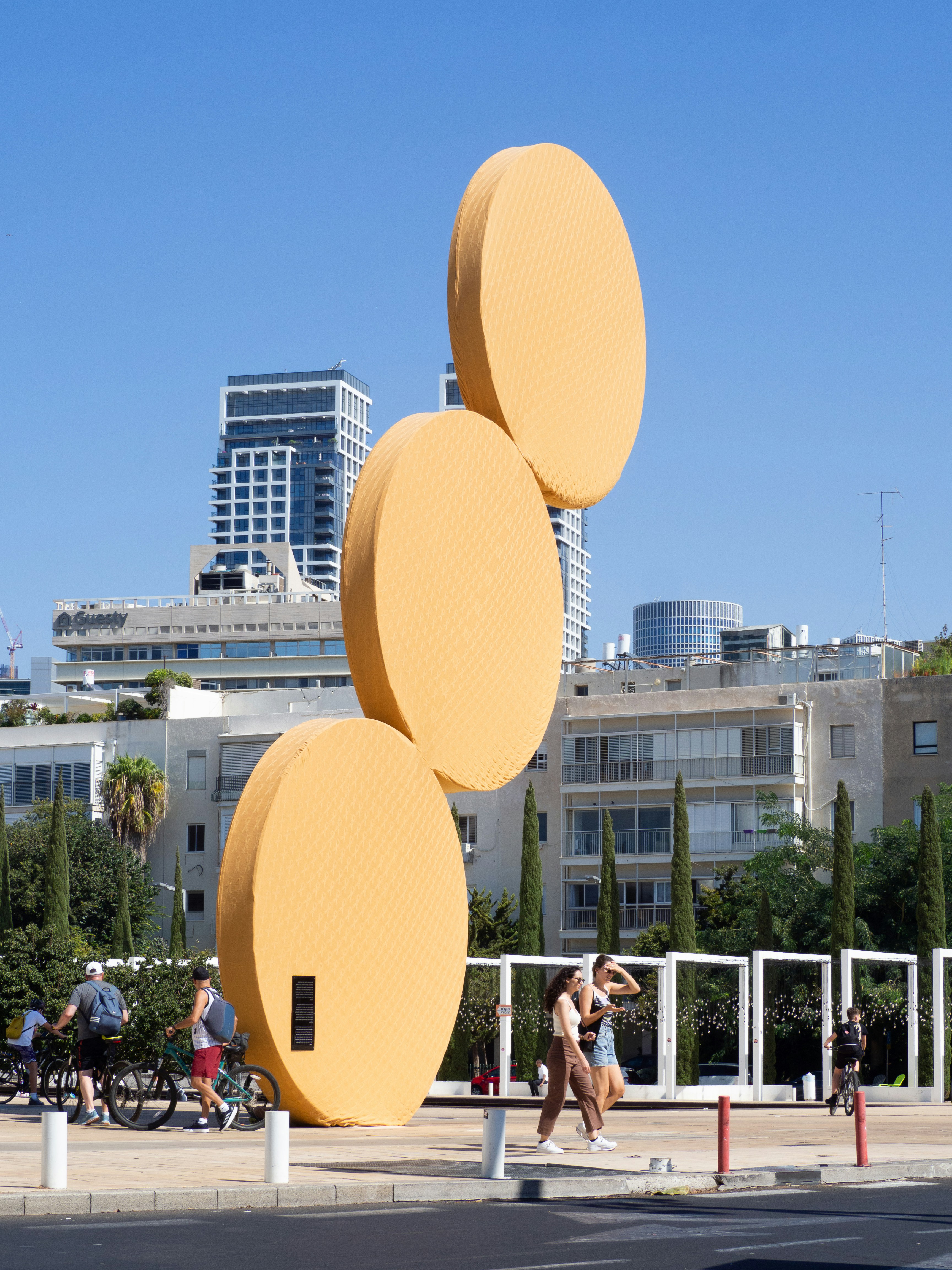 Un groupe de personnes passant devant une grande sculpture jaune