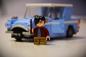 A lego figurine of a man with a gun next to a police car