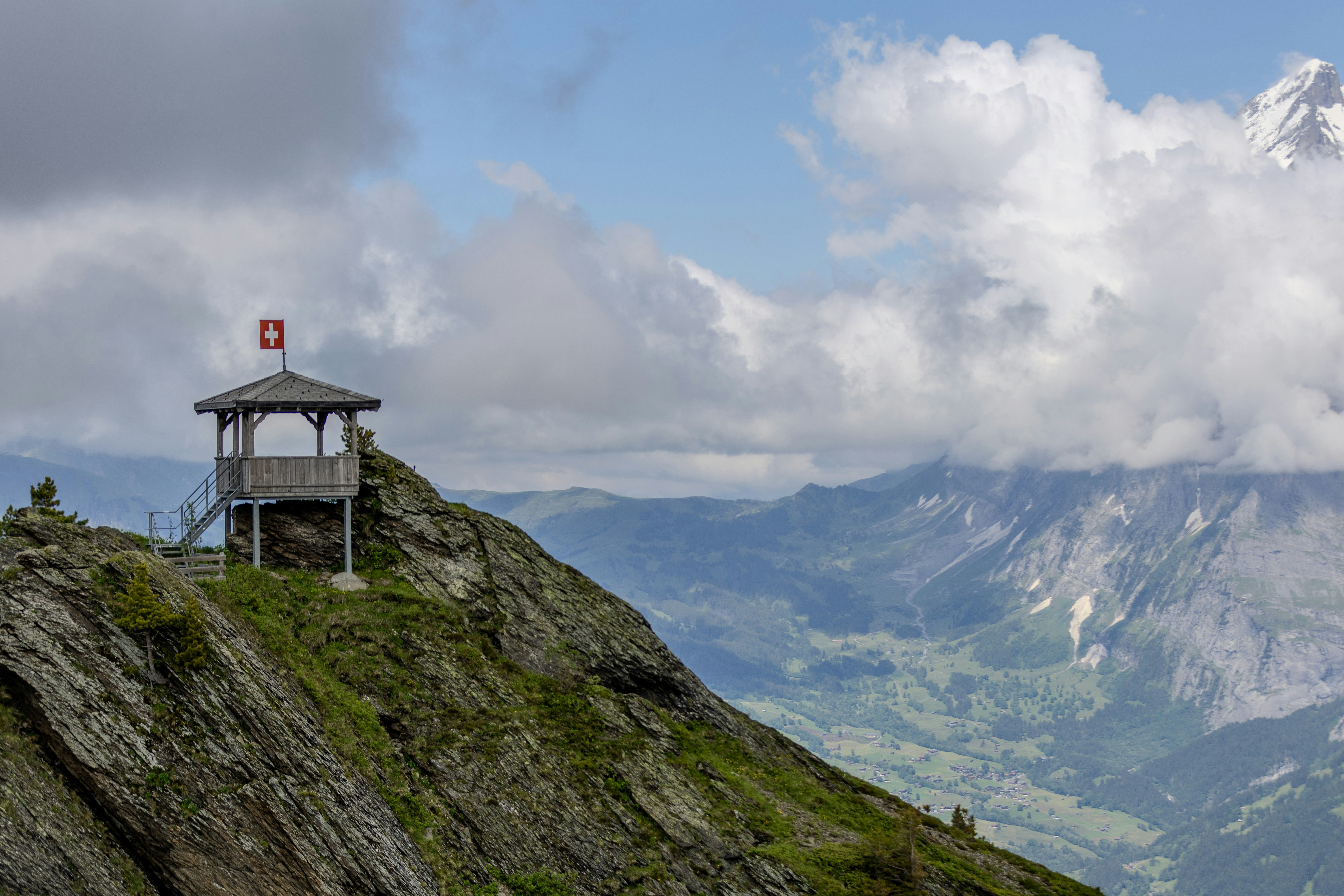 A gazebo on top of a mountain with mountains in the background