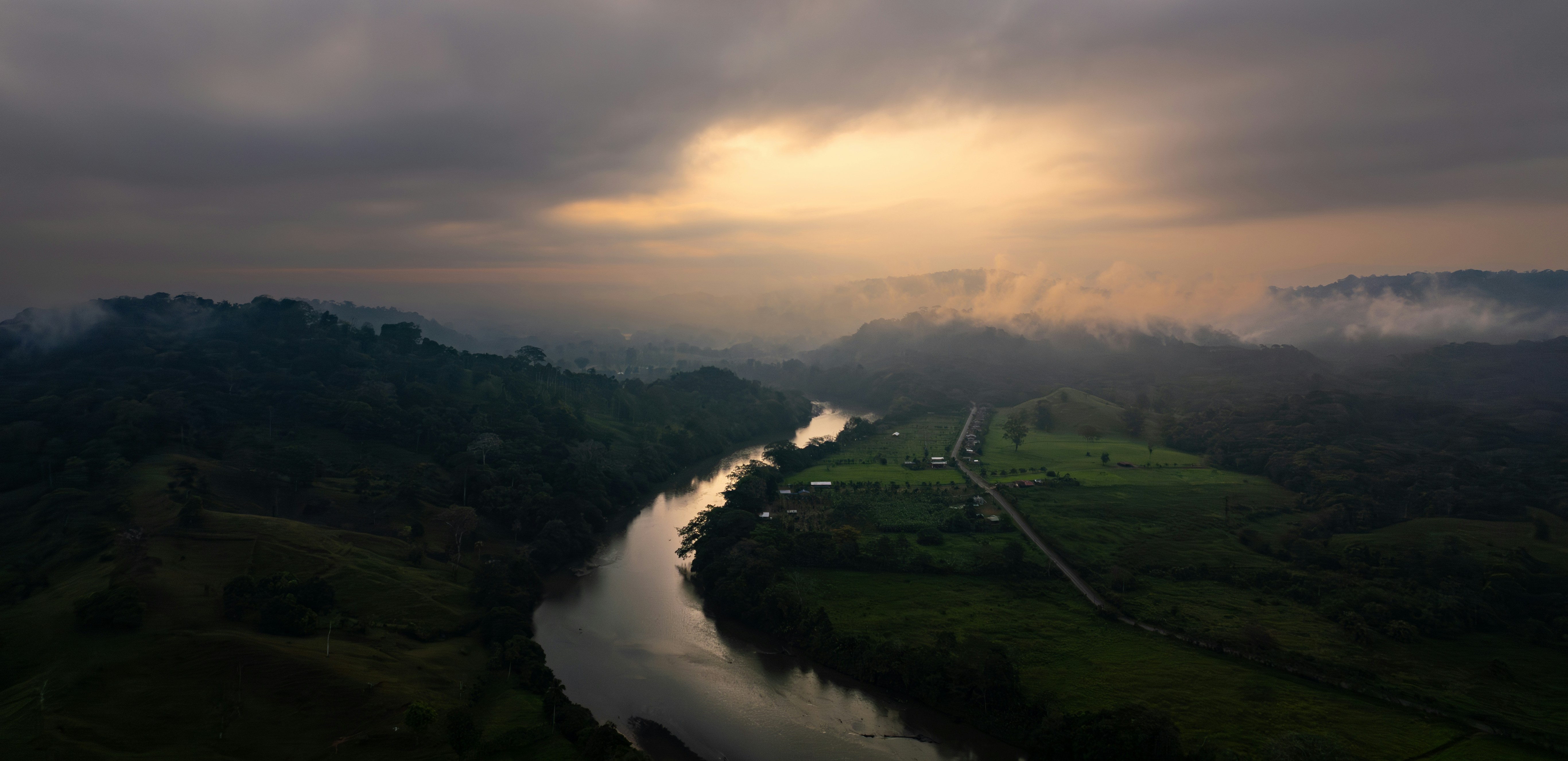 A river running through a lush green forest under a cloudy sky photo ...
