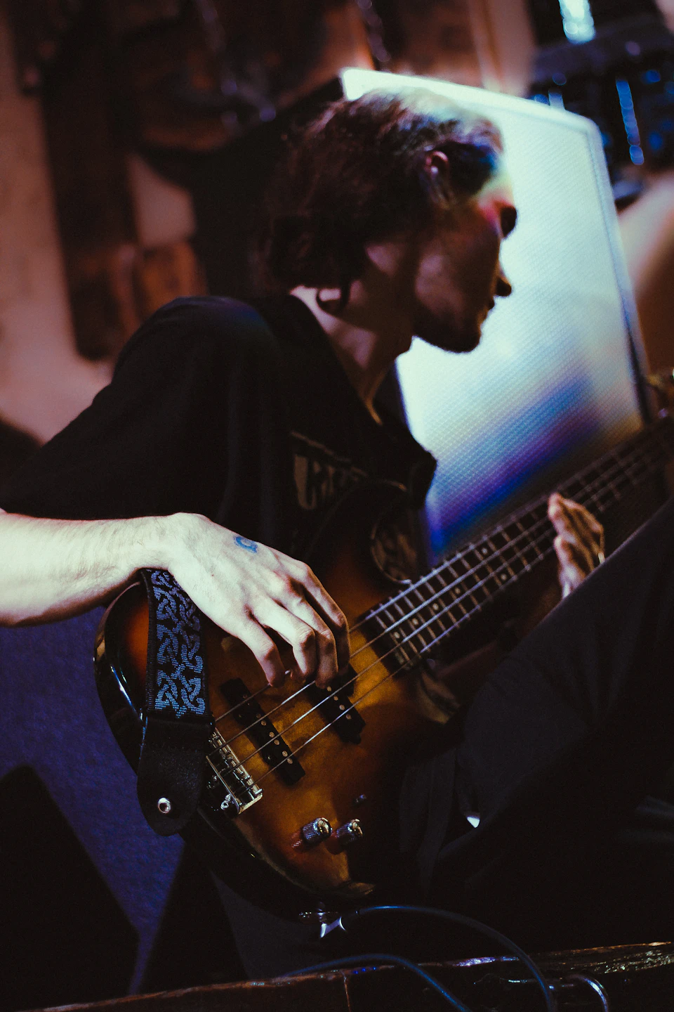 Man playing brown bass guitar with right hand while resting left hand on knee