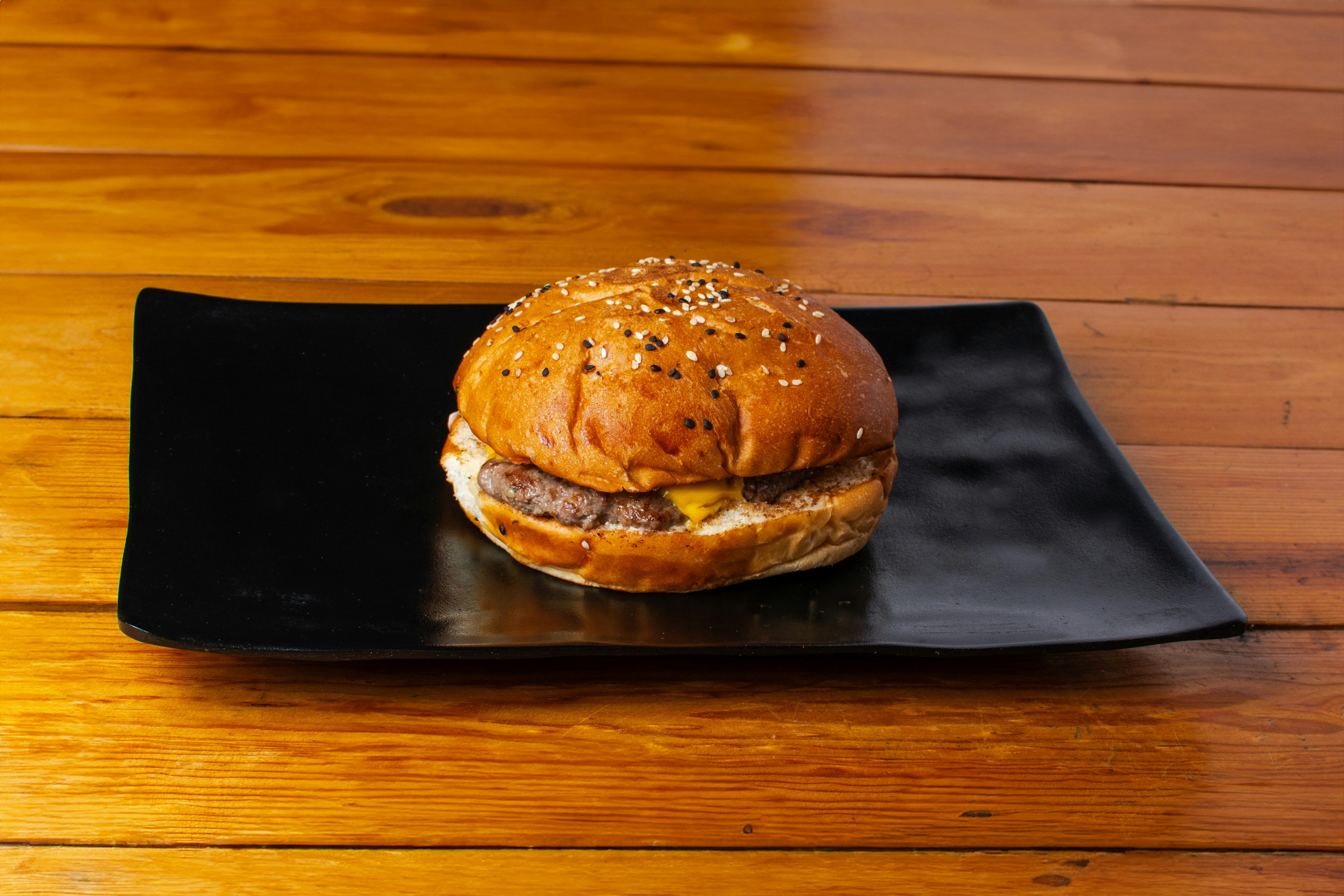 A hamburger on a black plate on a wooden table