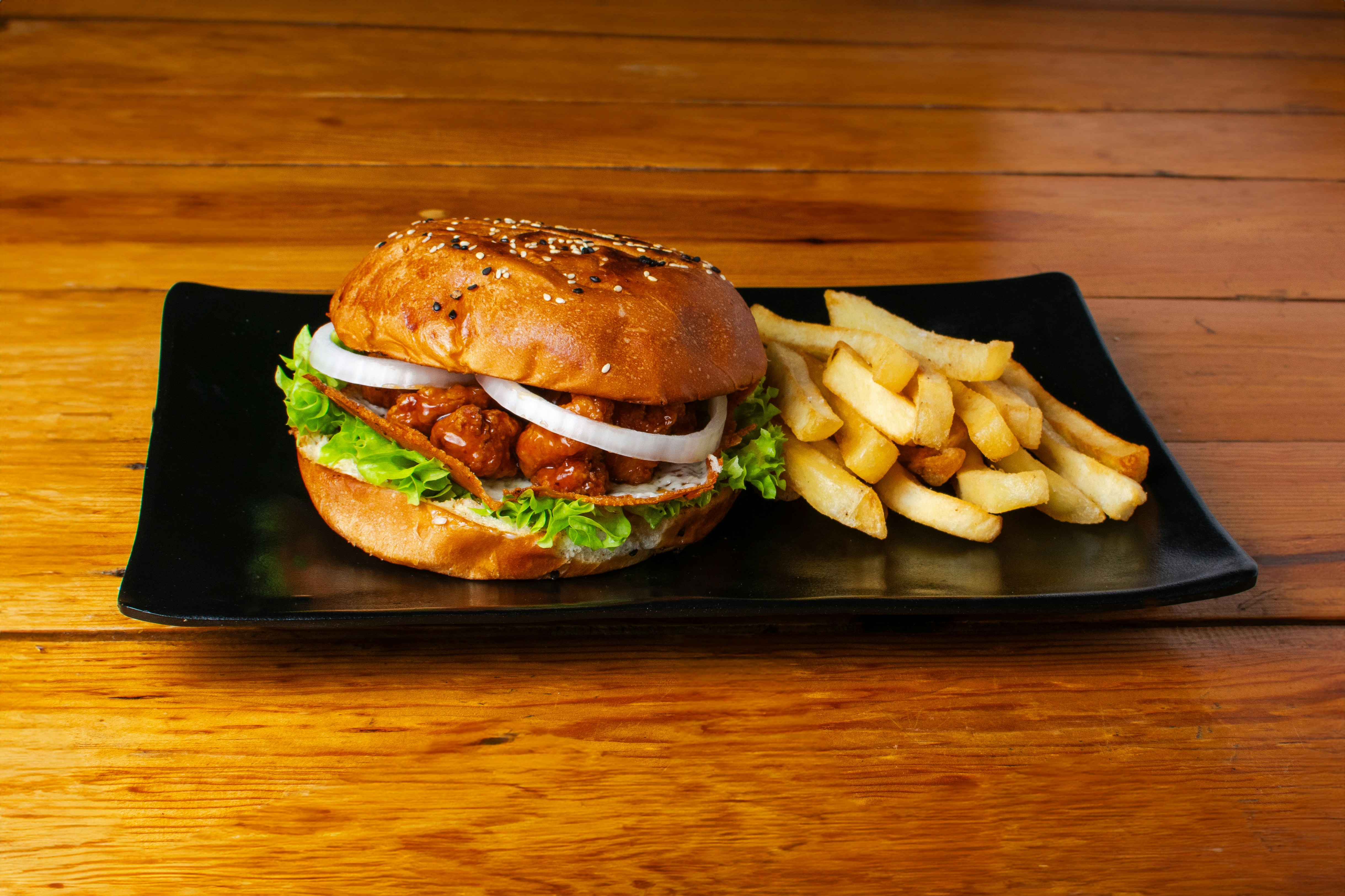A sandwich and french fries on a black plate