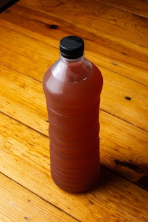 A red plastic bottle sitting on top of a wooden floor