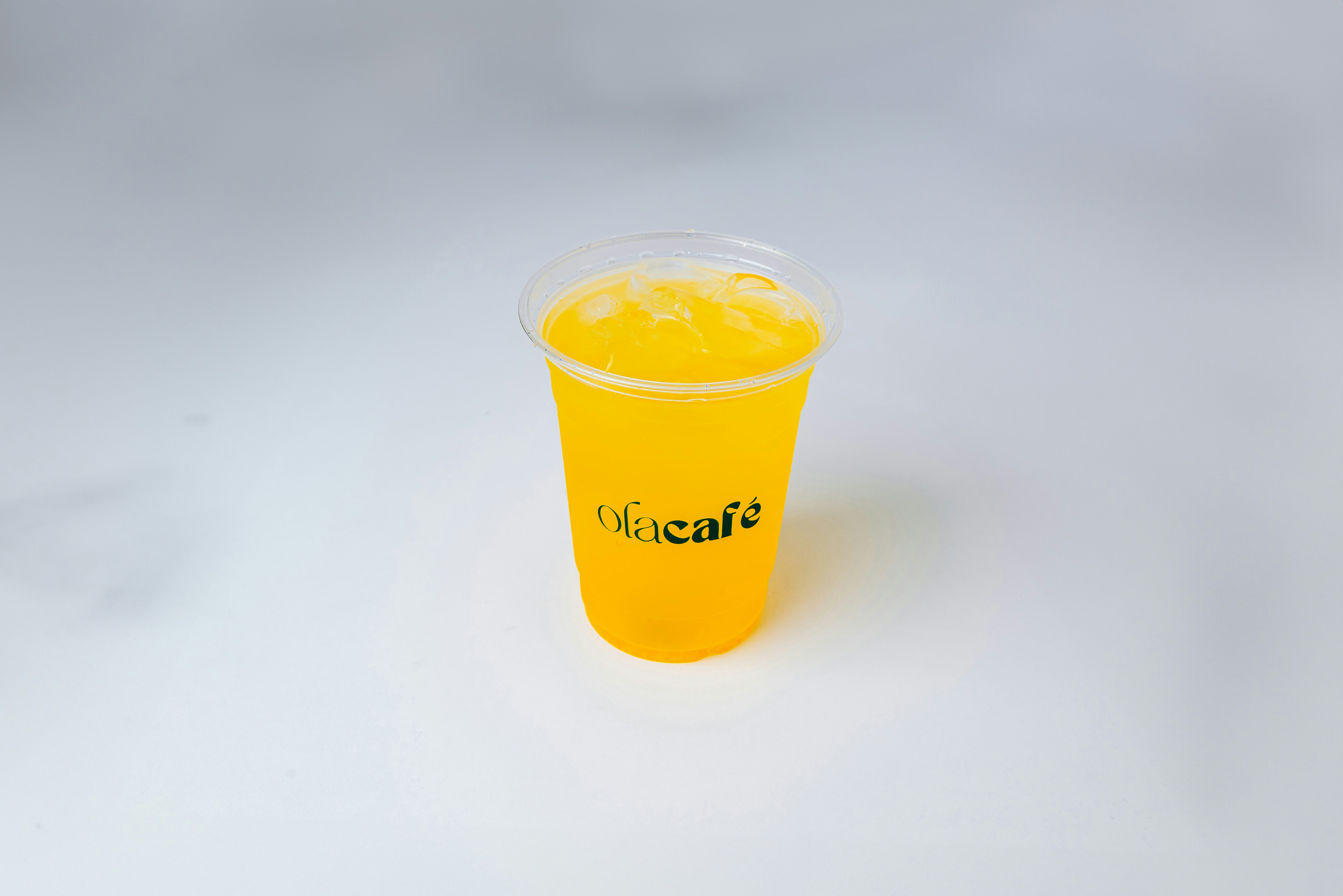 A cup of orange juice on a white surface