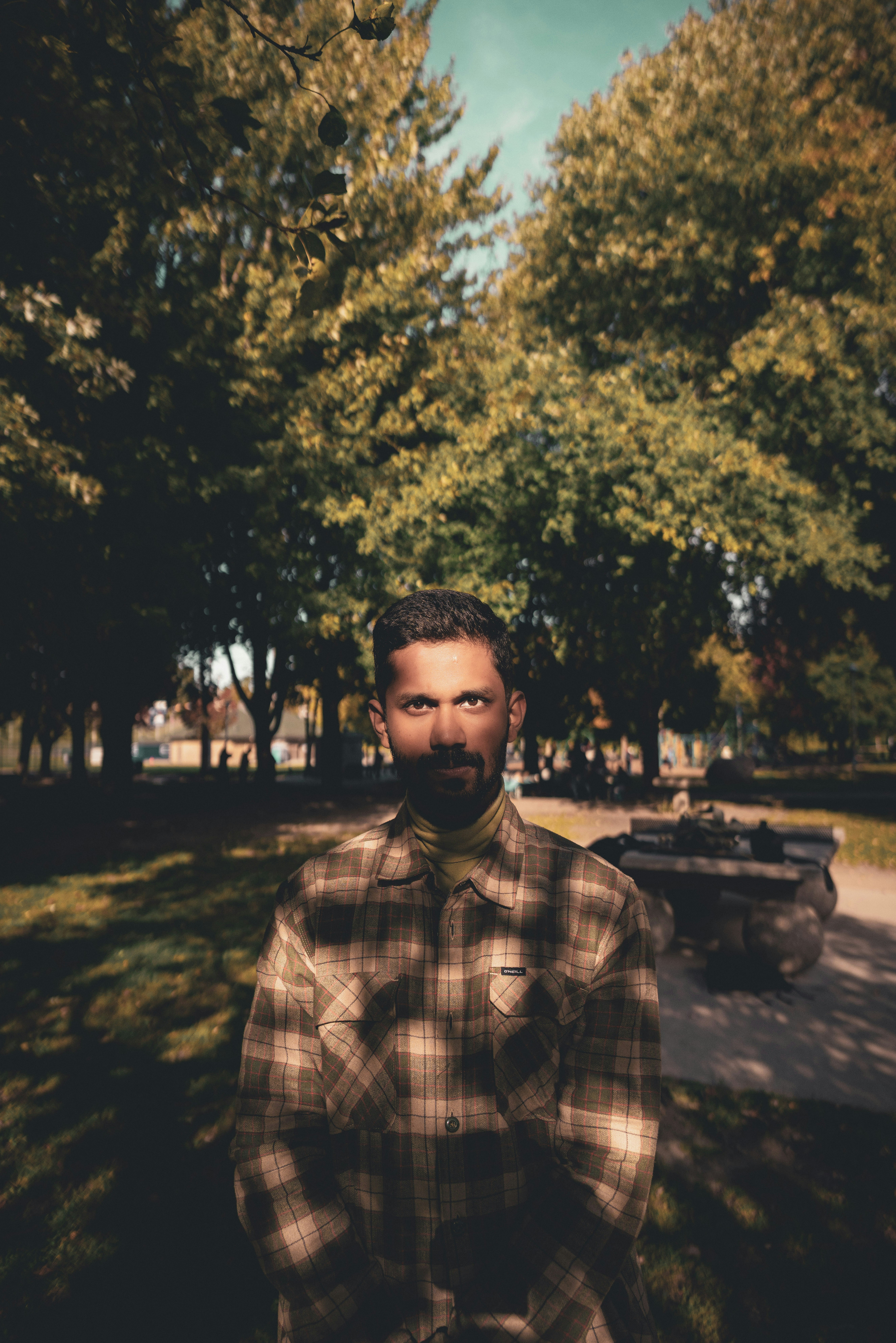 A man standing in a park with trees in the background