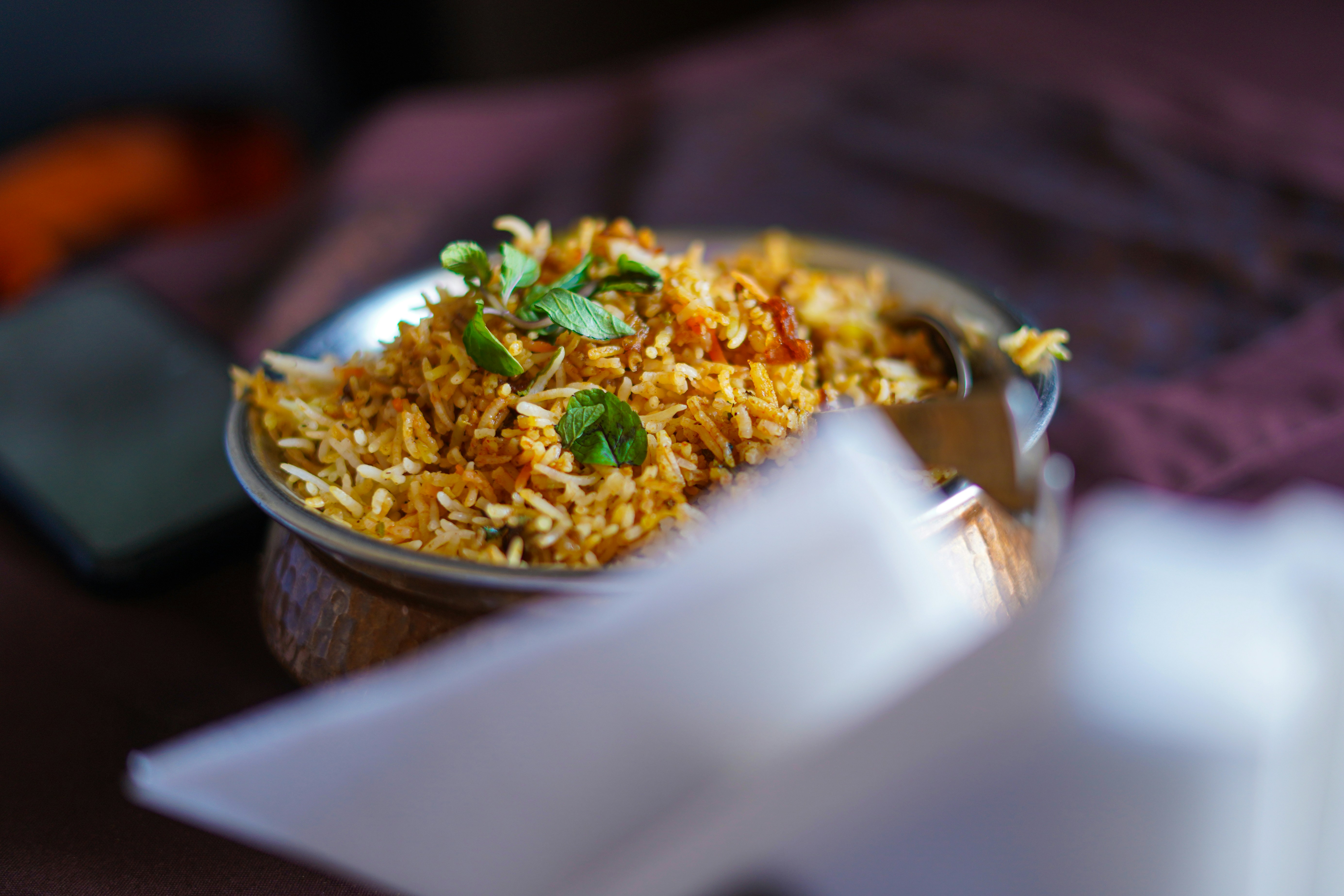 Close-up of saffron biryani in copper pot, vibrant golden rice with herbs