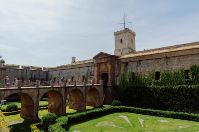 A bridge over a lush green field next to a tall building