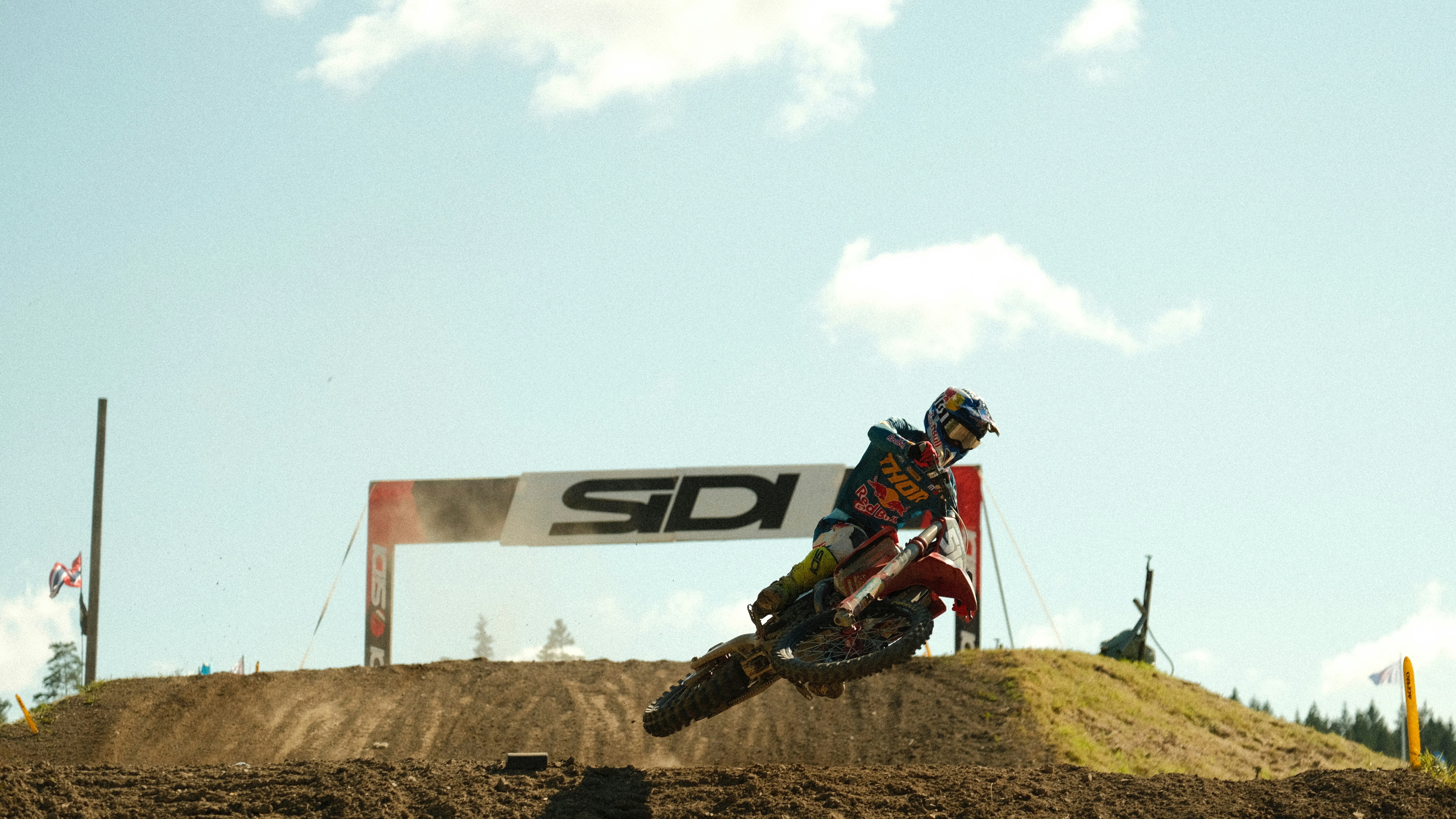A man riding a dirt bike on top of a dirt hill