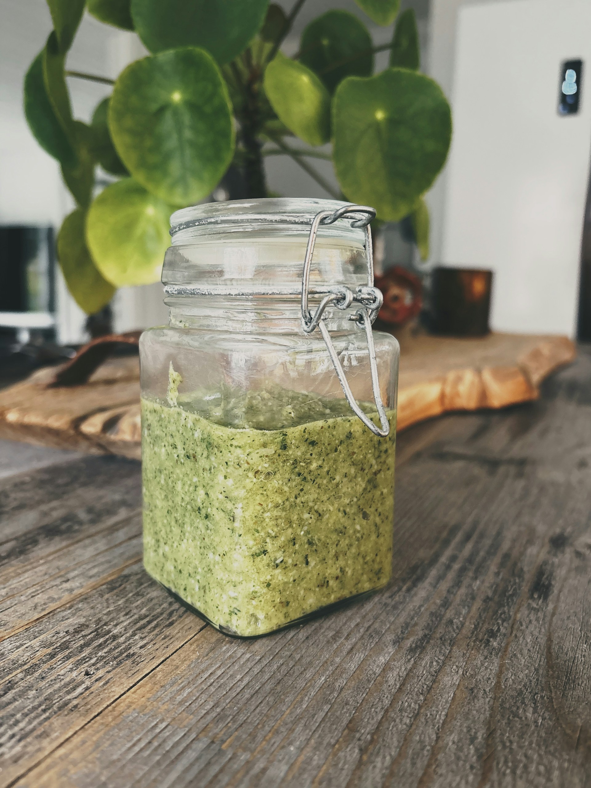 A jar filled with green stuff sitting on top of a wooden table
