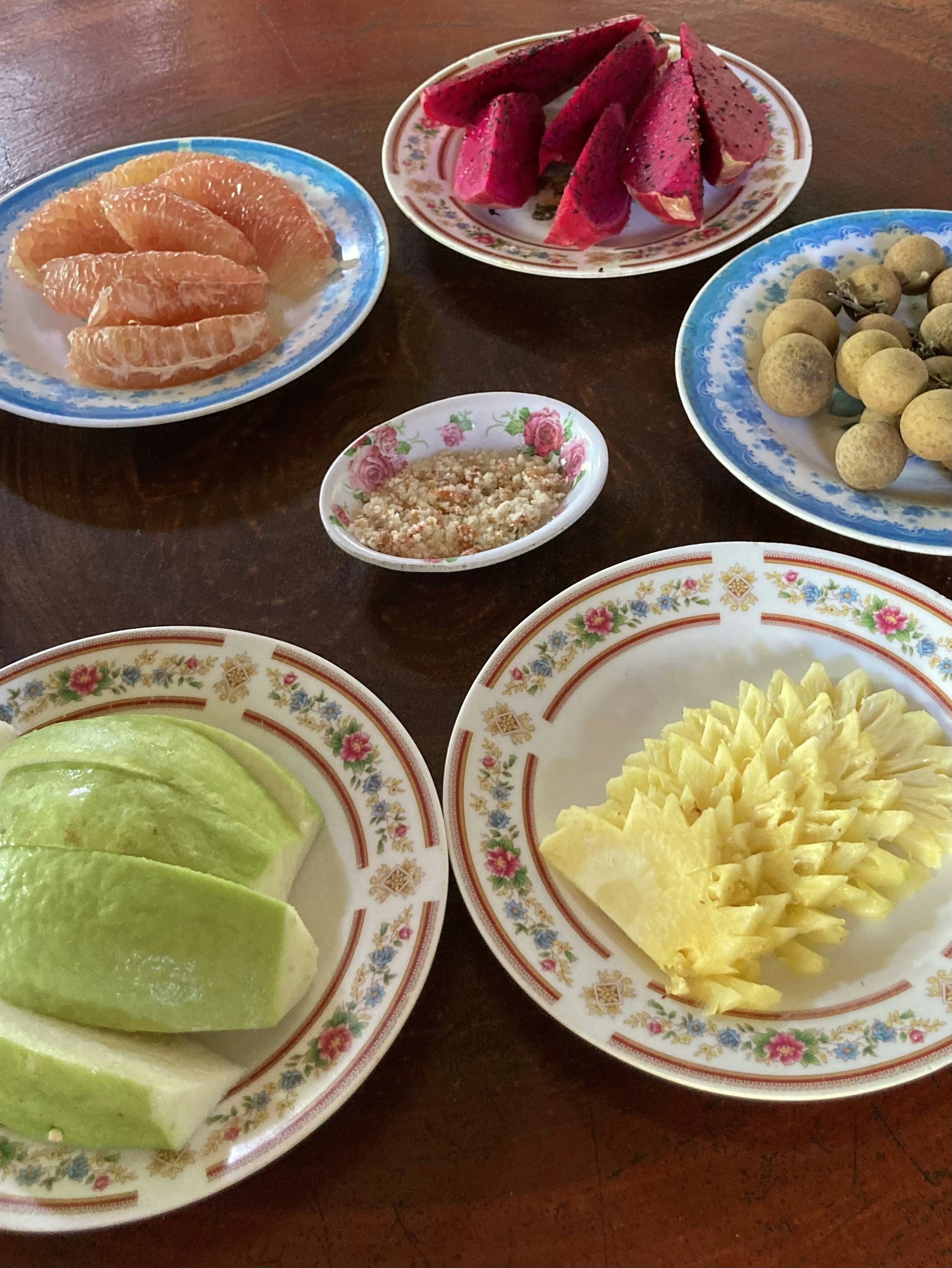 Colorful assortment of fresh tropical fruits including mangoes and guavas on wooden surface