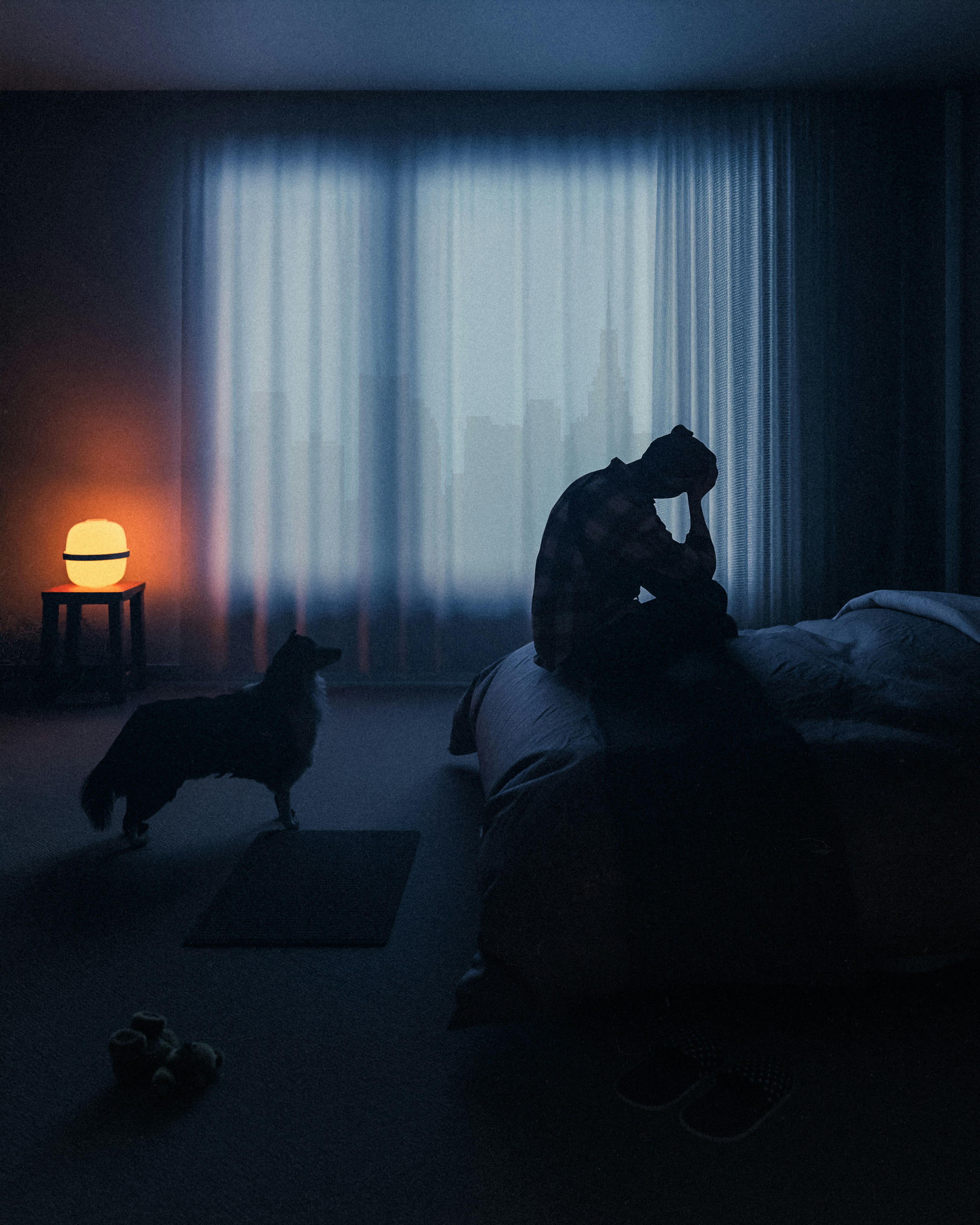 A person sitting on a bed in a dark room