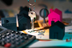 A calculator, keychain, and house model on a table