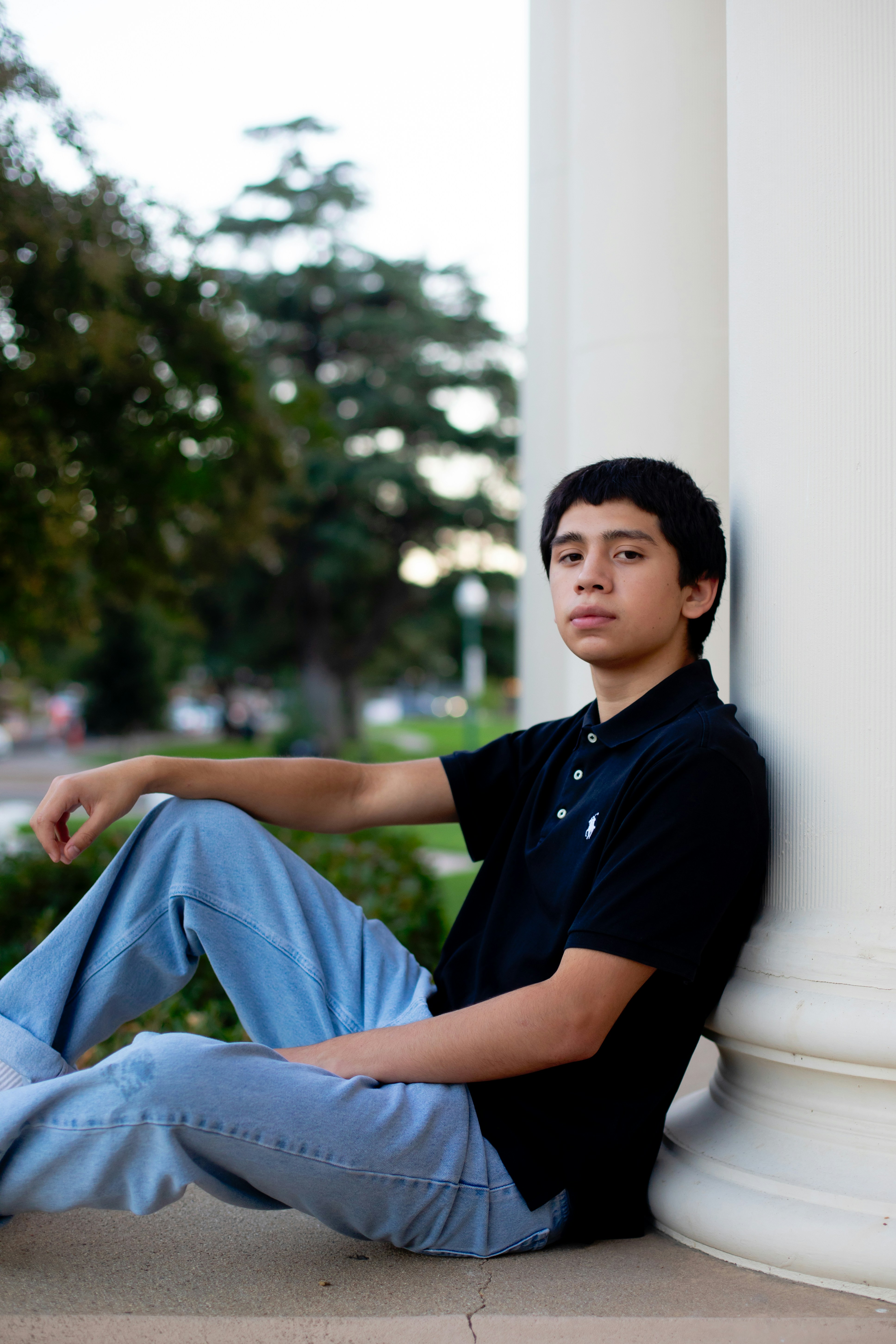 A young man sitting on the side of a building