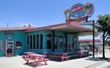 A blue and pink building with a pink picnic table outside of it
