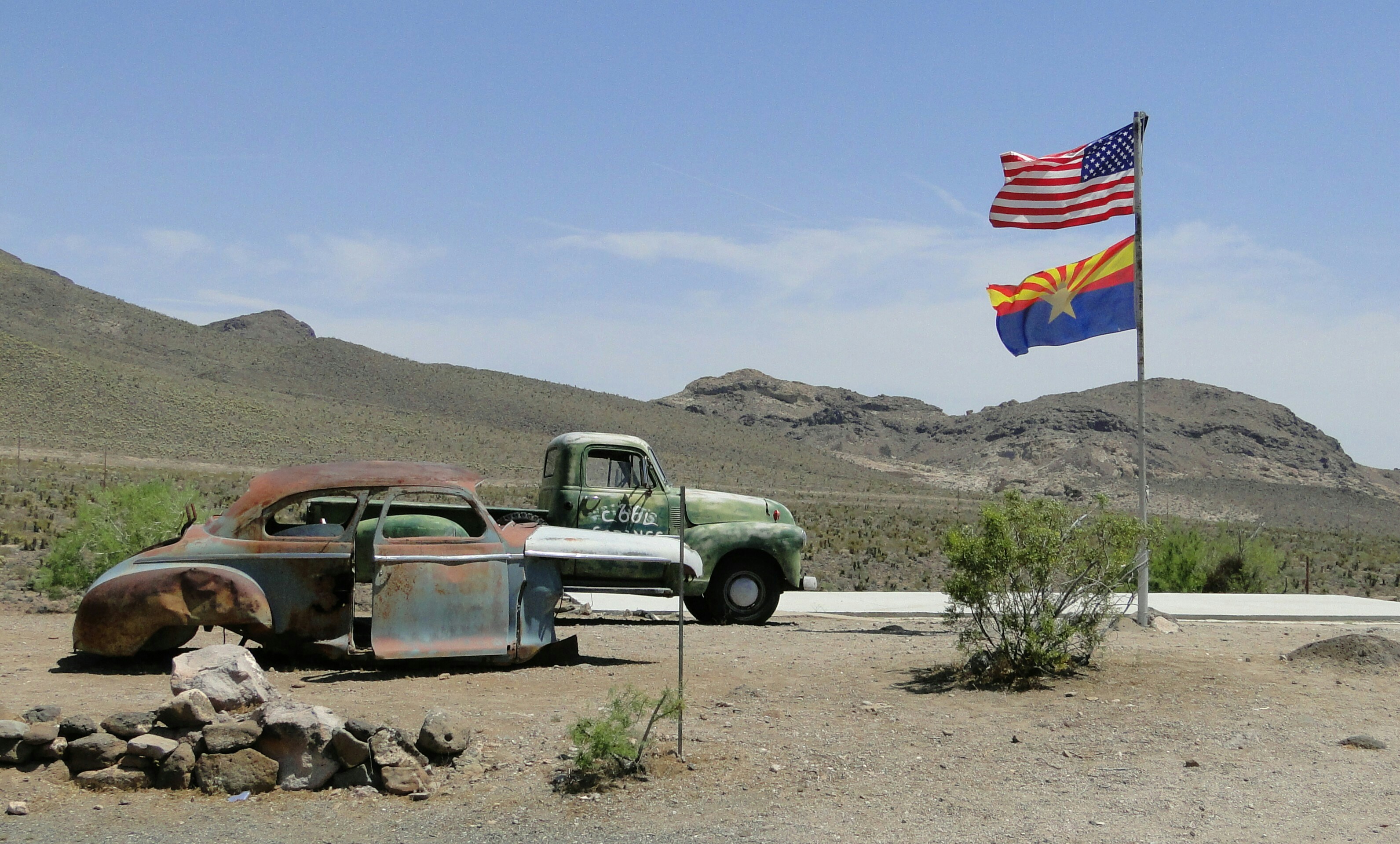 Two old trucks are parked in the desert