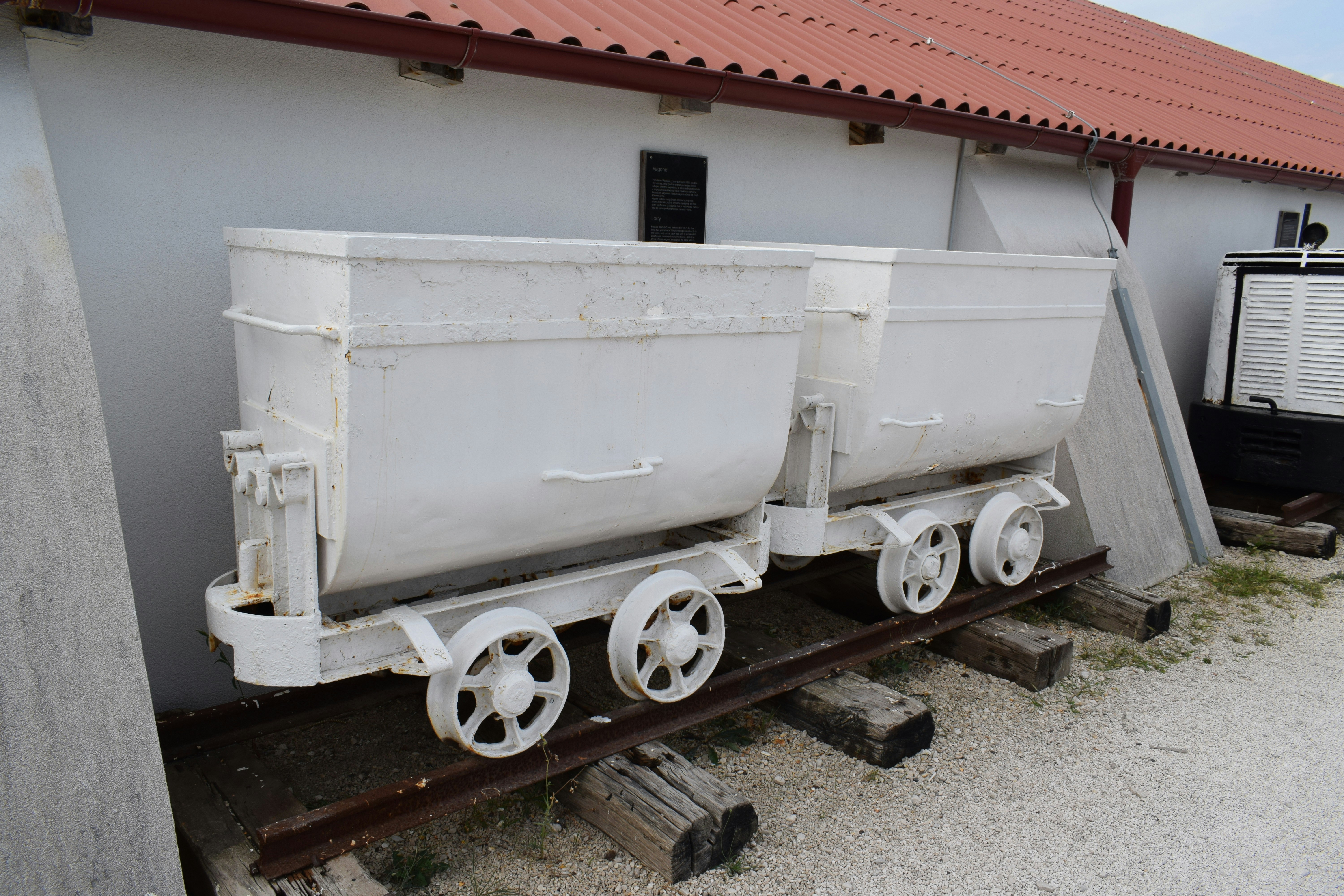 A train car sitting on the tracks next to a building