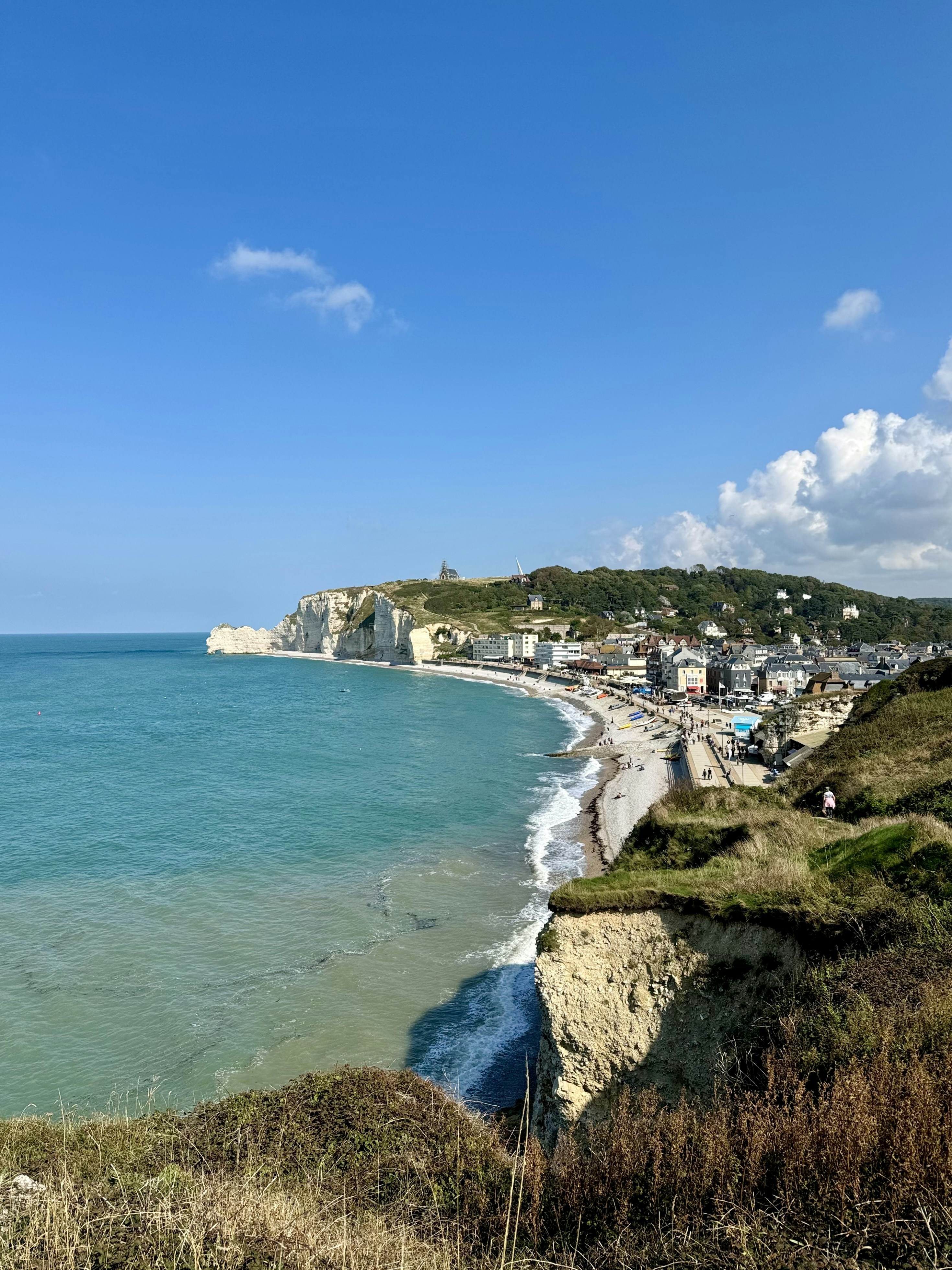 A view of a beach from a hill overlooking the ocean