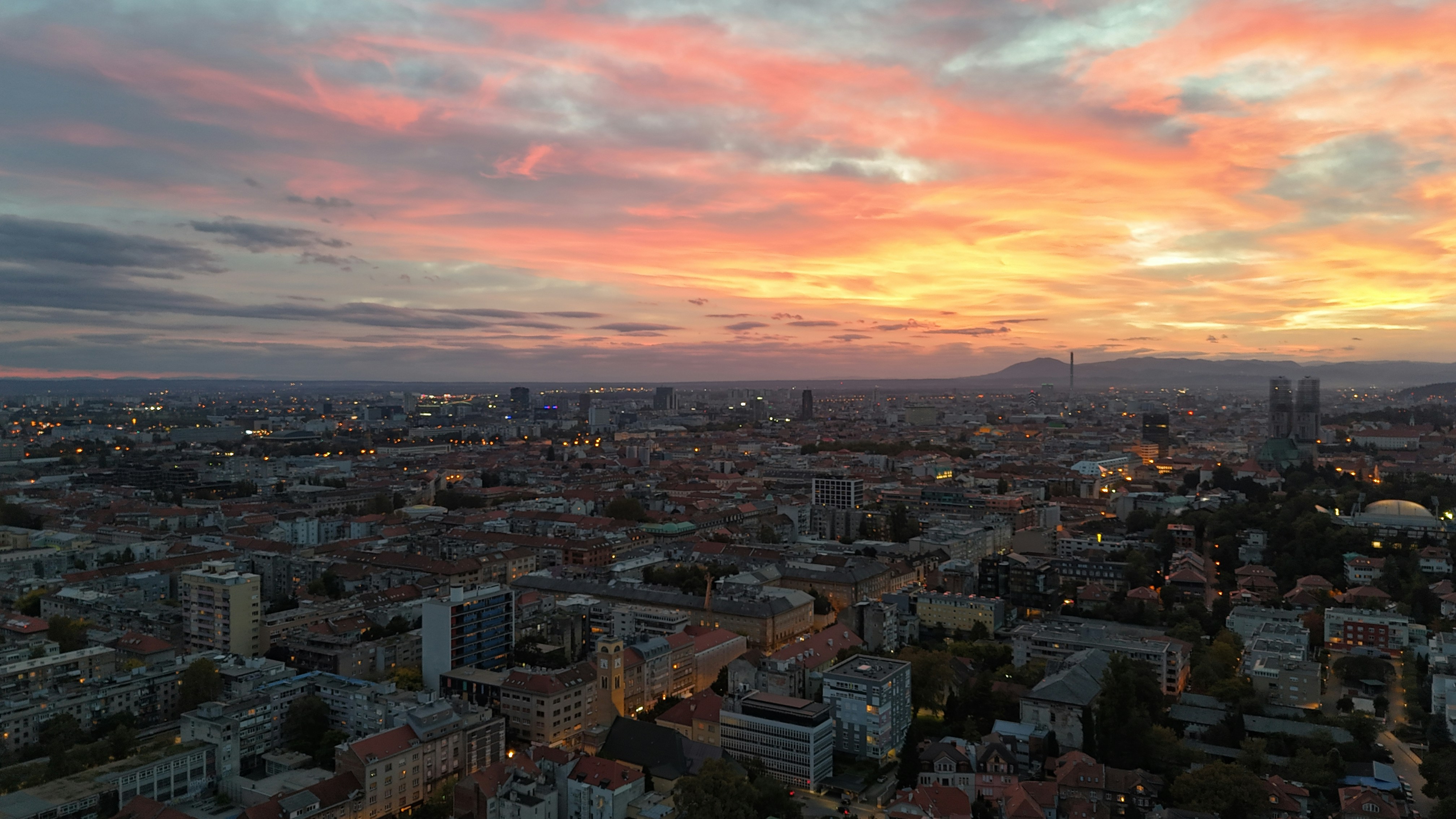 A view of a city at sunset from the top of a building