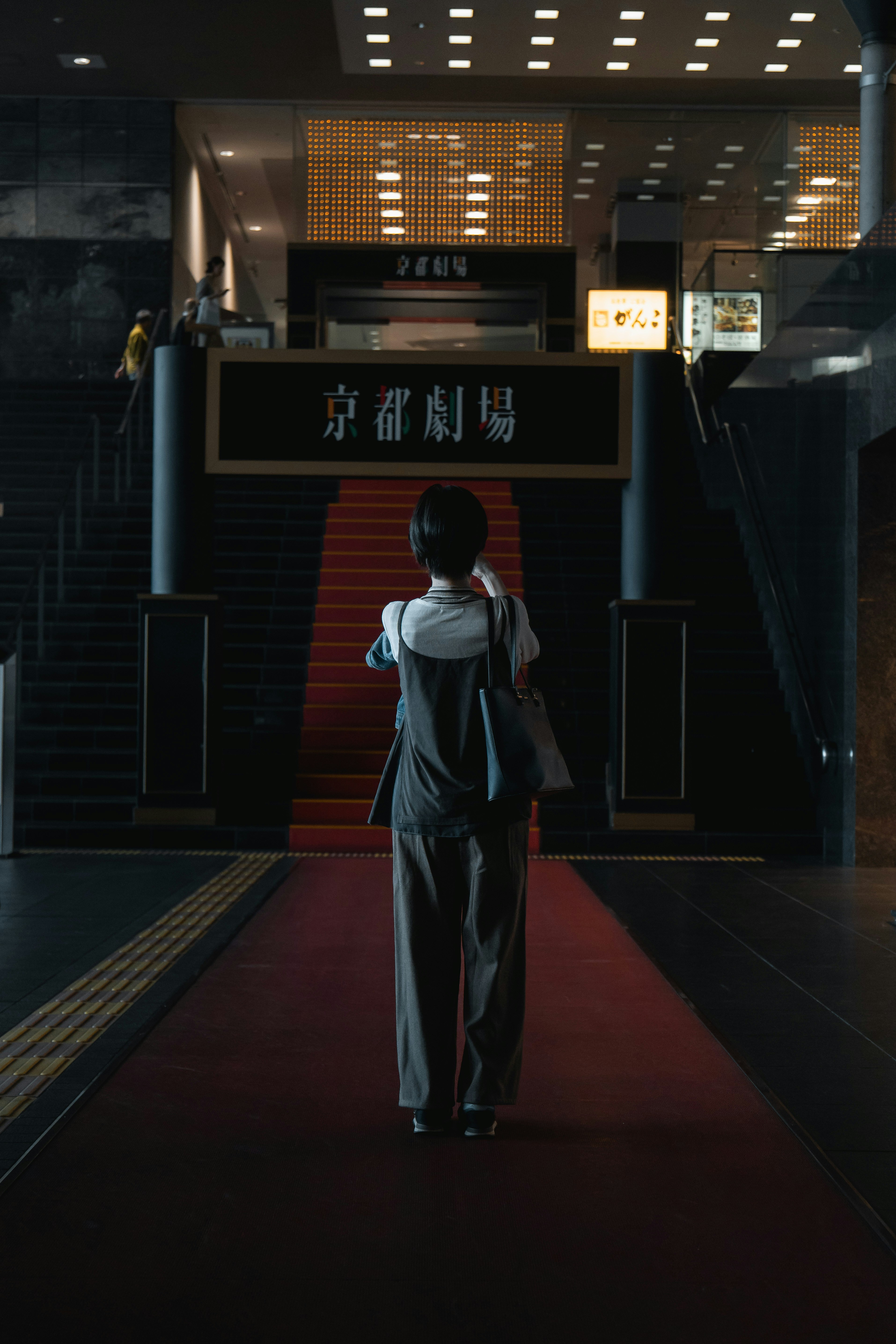 A woman walking down a red carpeted hallway