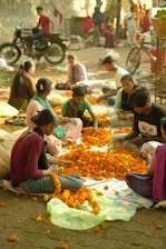 A group of people sitting around a pile of oranges