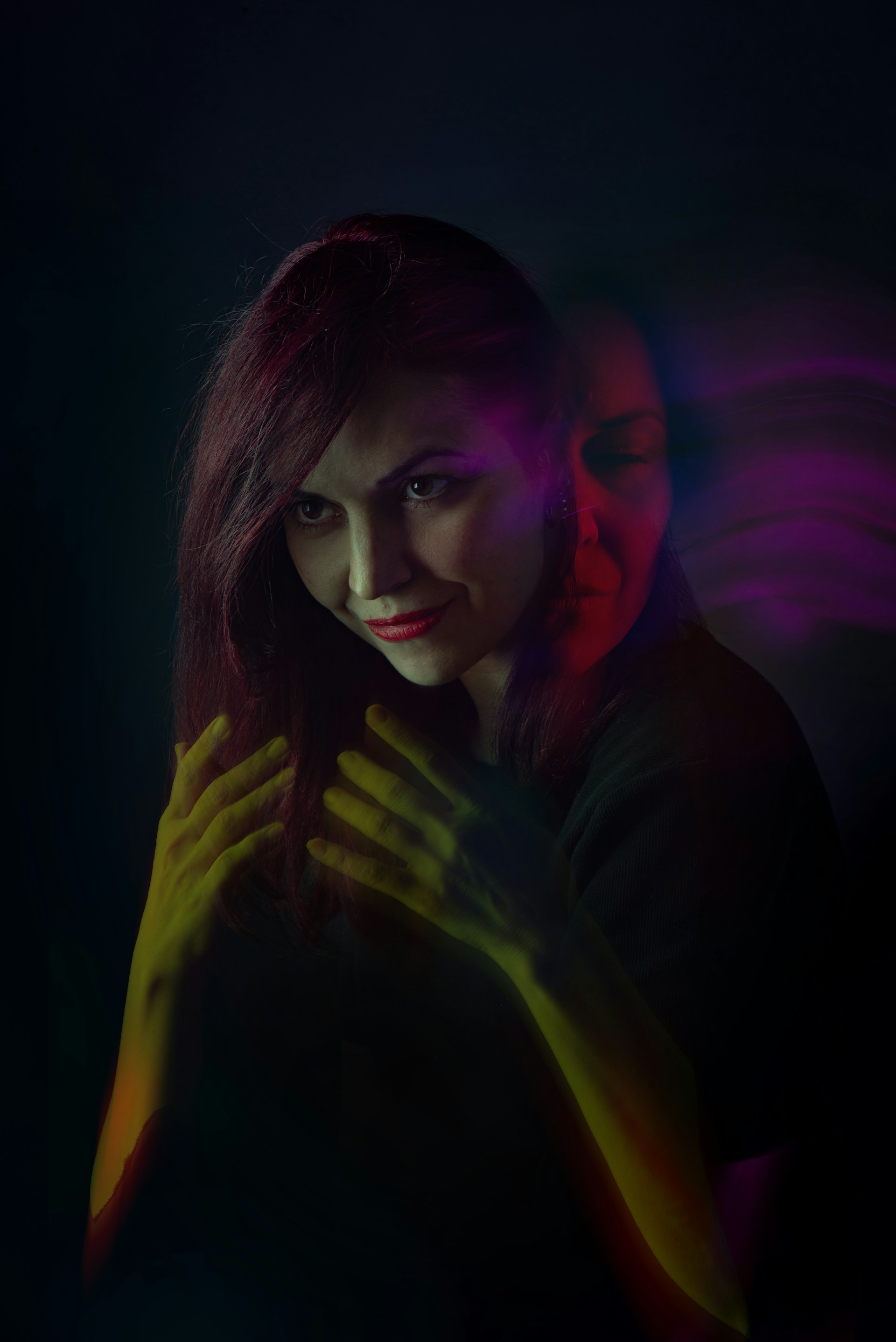 A woman standing in the dark with her hands on her chest