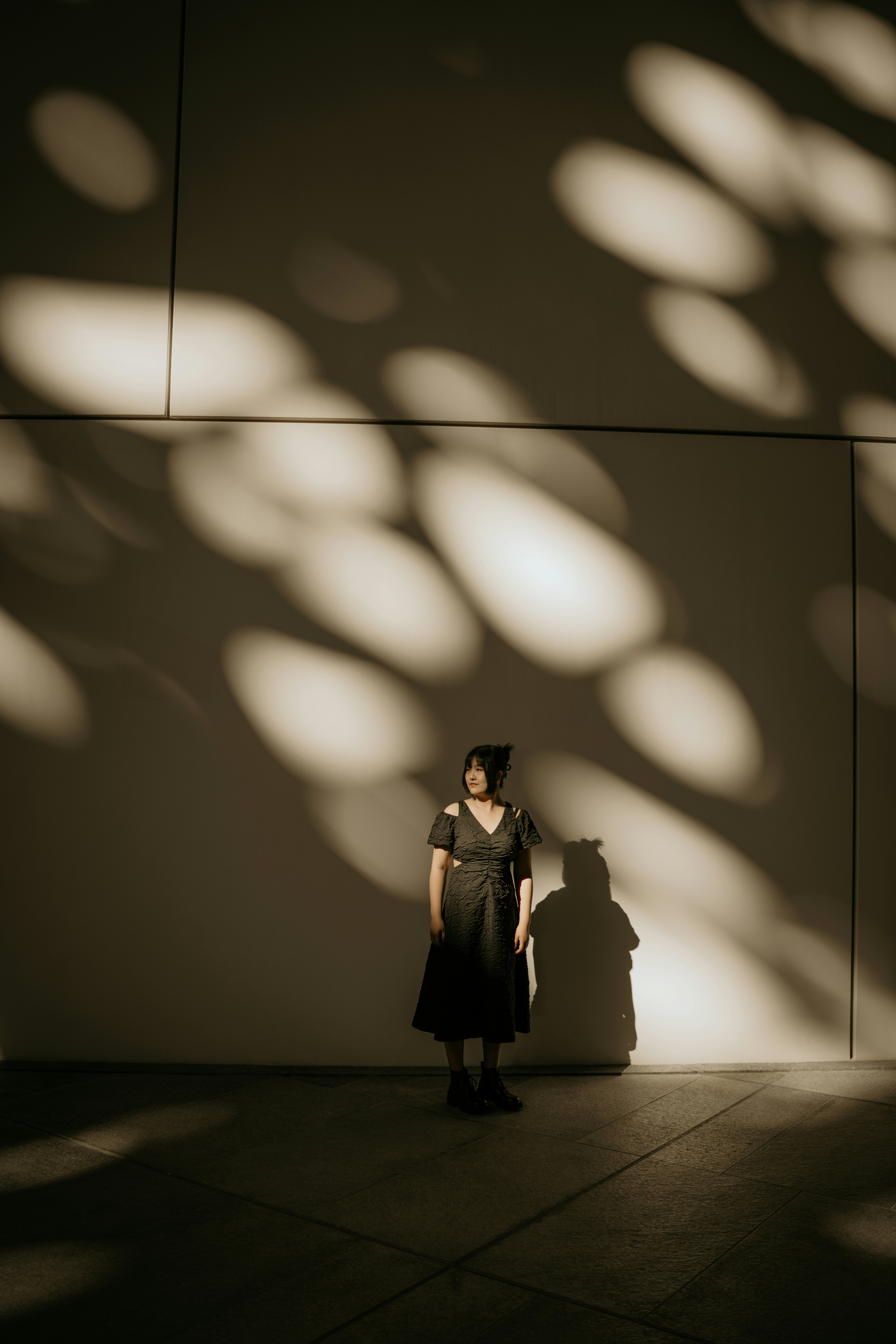 A woman standing in front of a wall with a shadow on it
