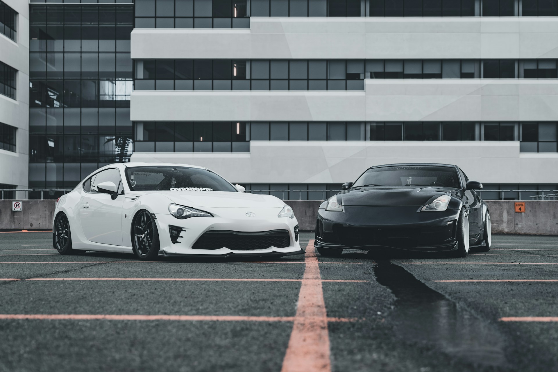 Two cars parked in a parking lot next to a tall building