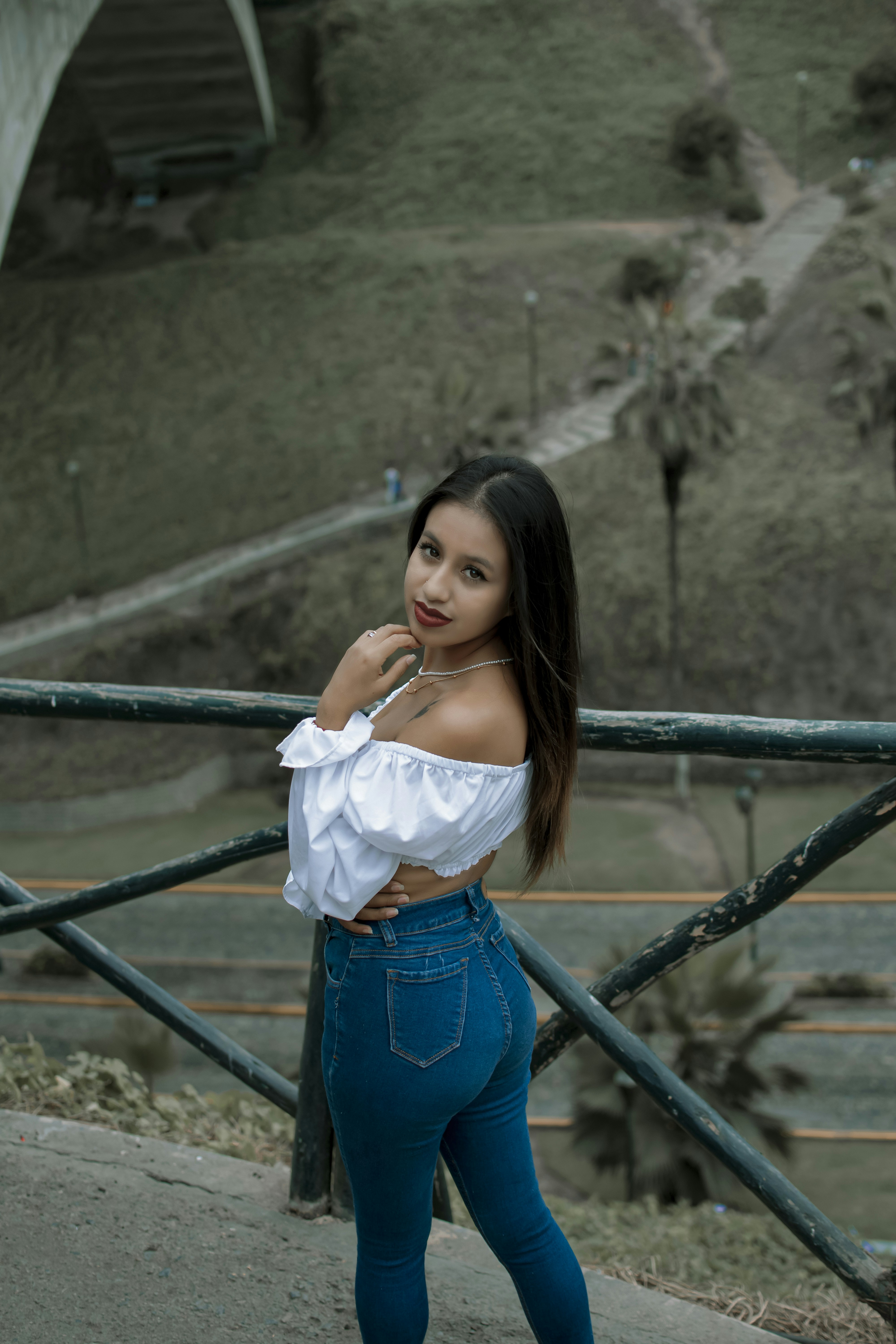 A woman in a white top and blue jeans posing for a picture photo – Free ...