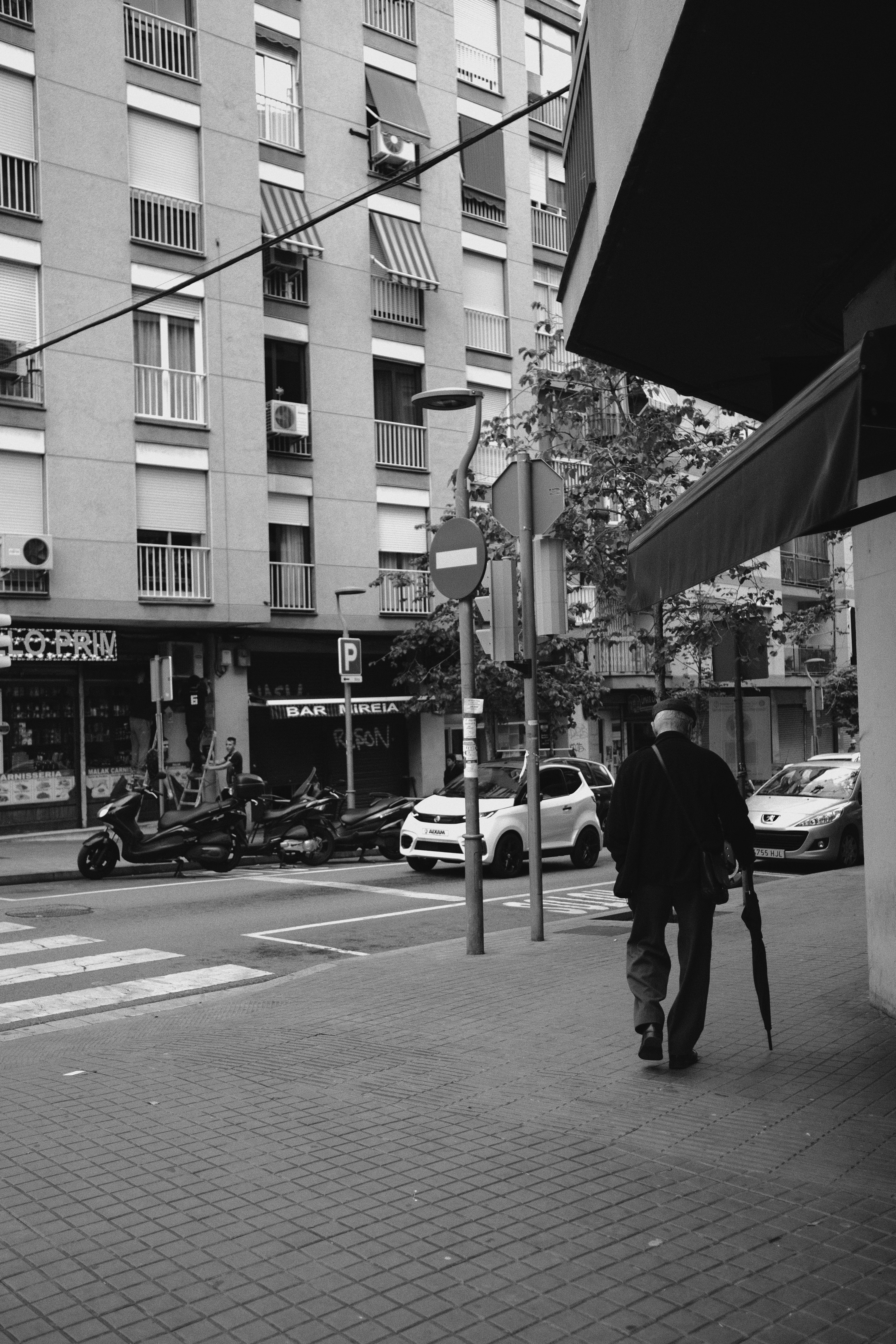A black and white photo of a man walking down the street