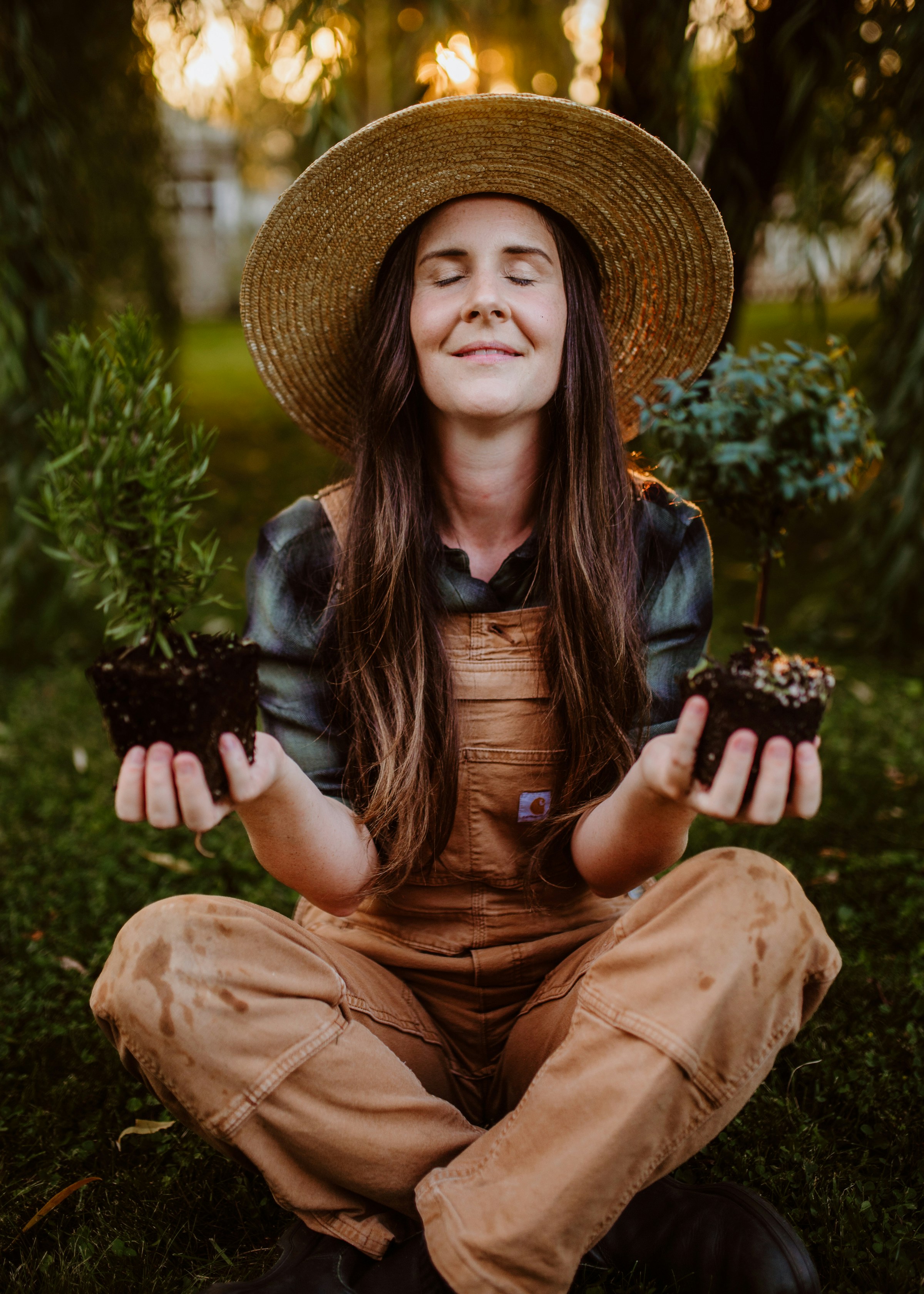 A woman in a hat is sitting in the grass