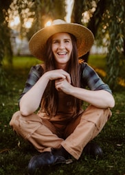 A woman wearing a hat sitting in the grass