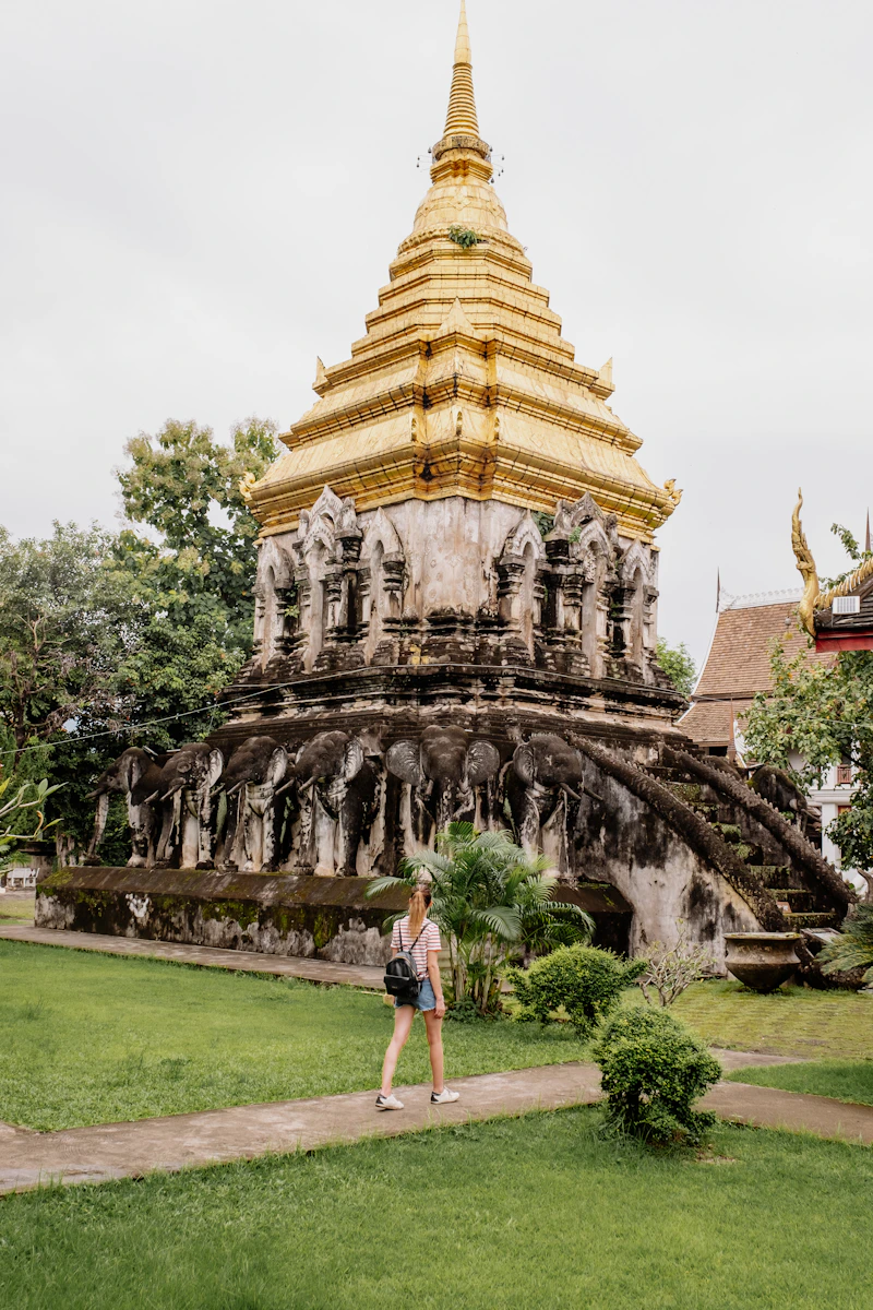 A woman walking in front of a golden pagoda
