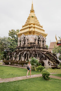 A woman walking in front of a golden pagoda