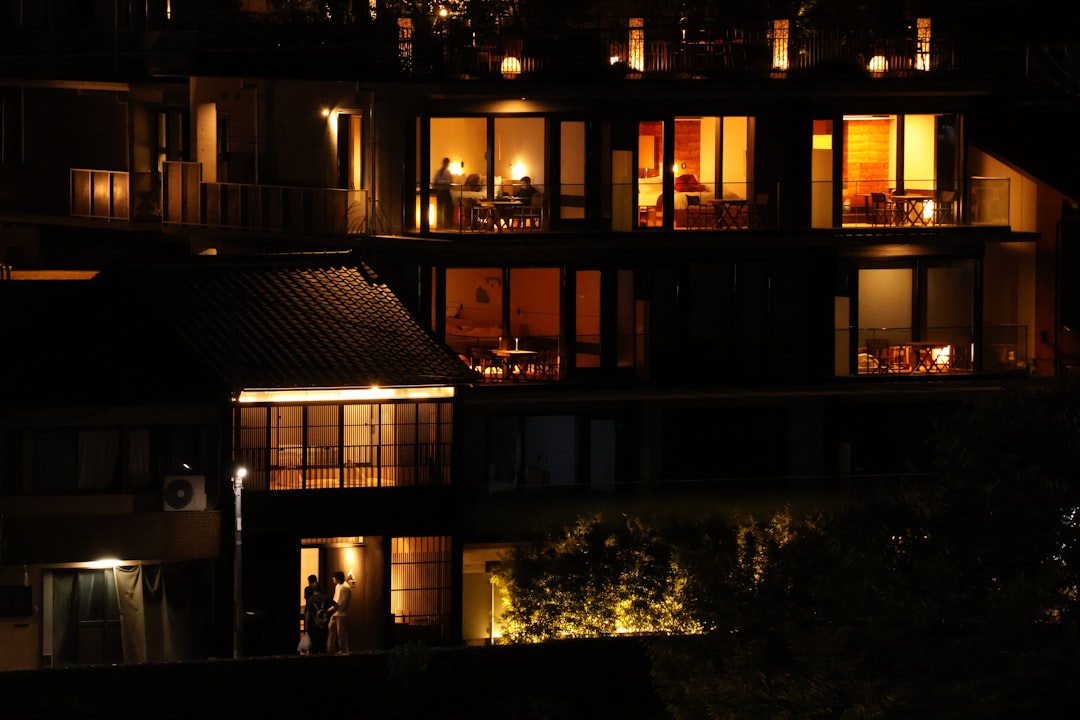 A building lit up at night with lights on, Genji Kyoto shoot from the other side of Kamogawa River in Kyoto