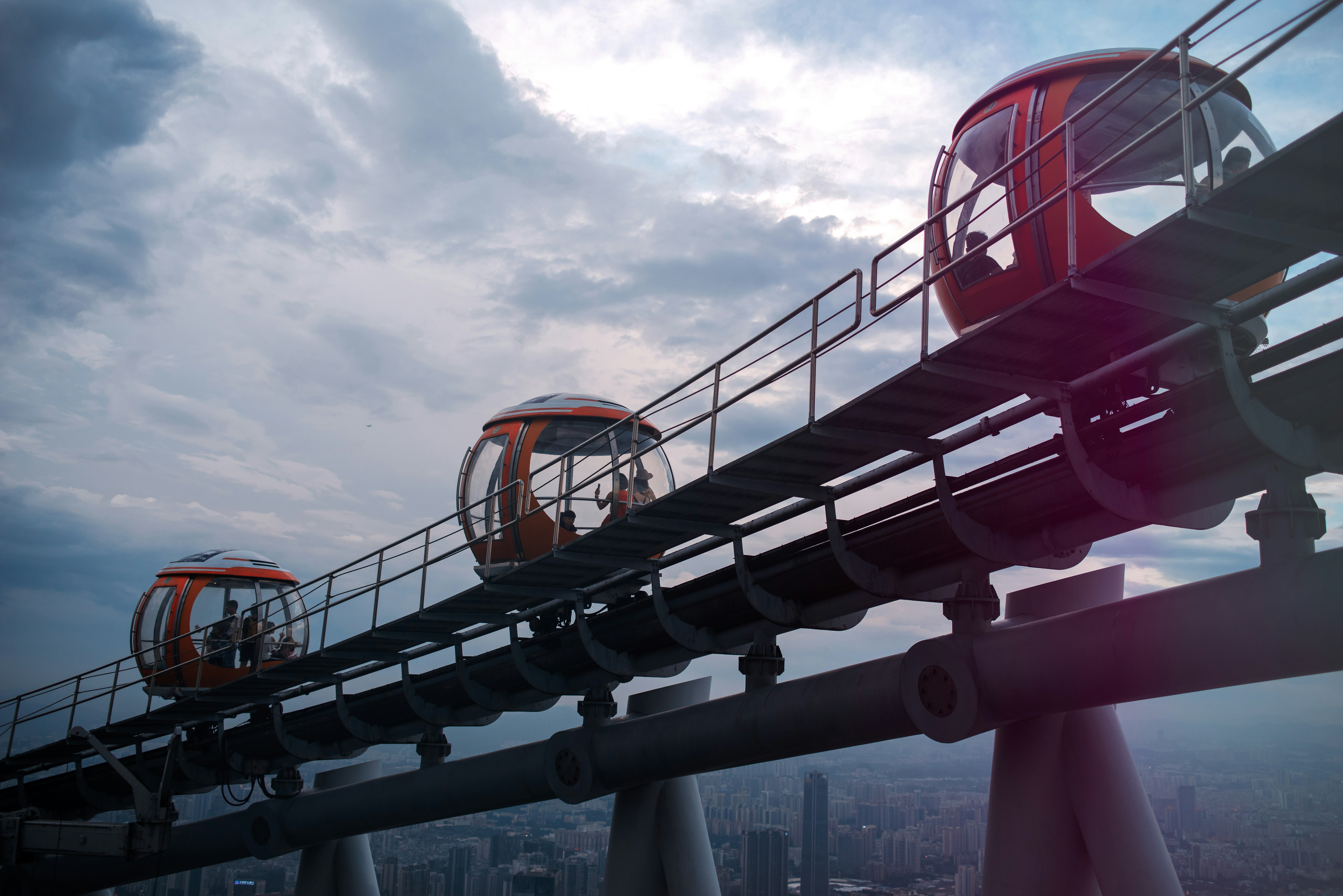 A roller coaster going over a bridge in a city