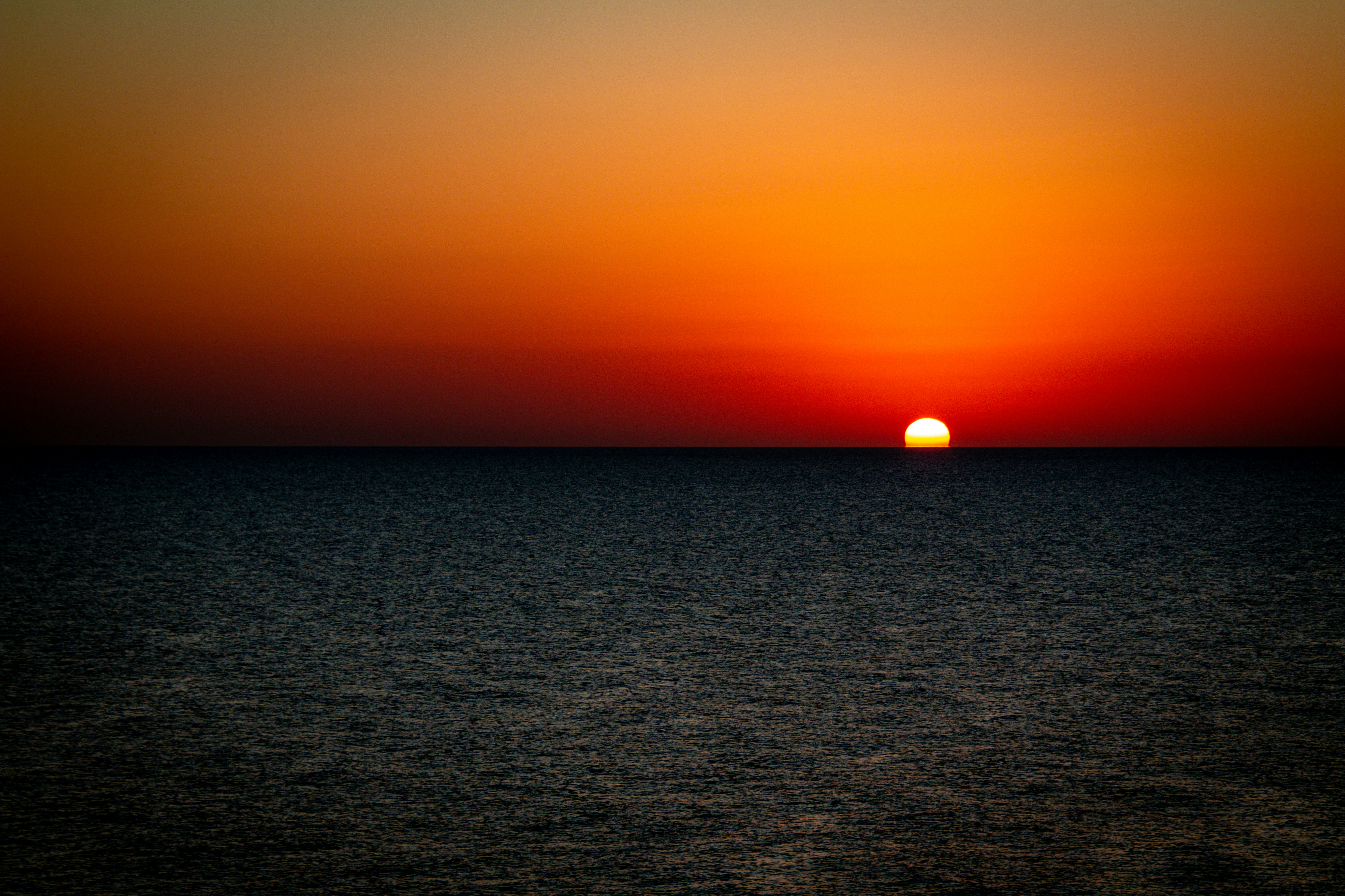 The sun is setting over the ocean on a clear day