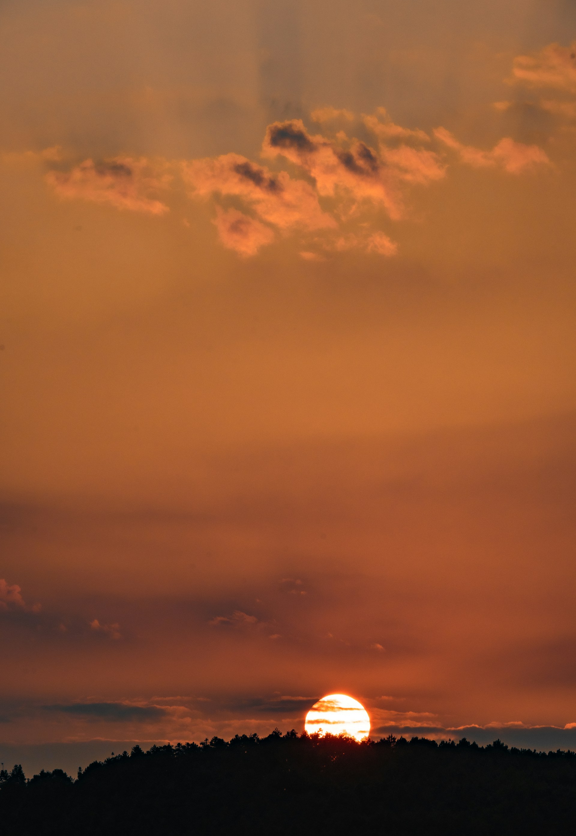 The sun is setting in the sky over a hill