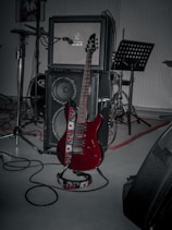 A red guitar sitting on top of a hard wood floor