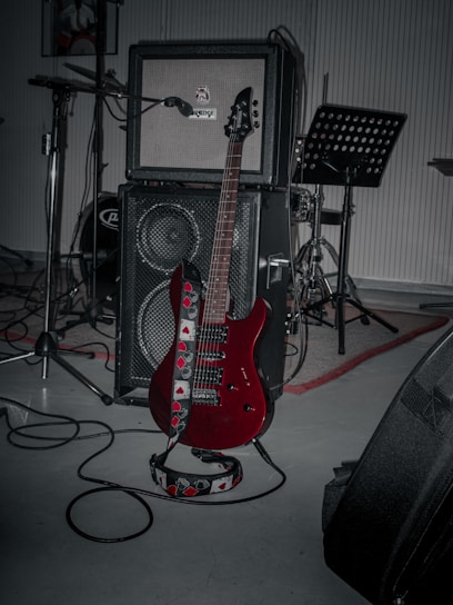 A red guitar sitting on top of a hard wood floor