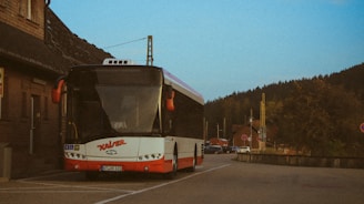A red and white bus parked in front of a building