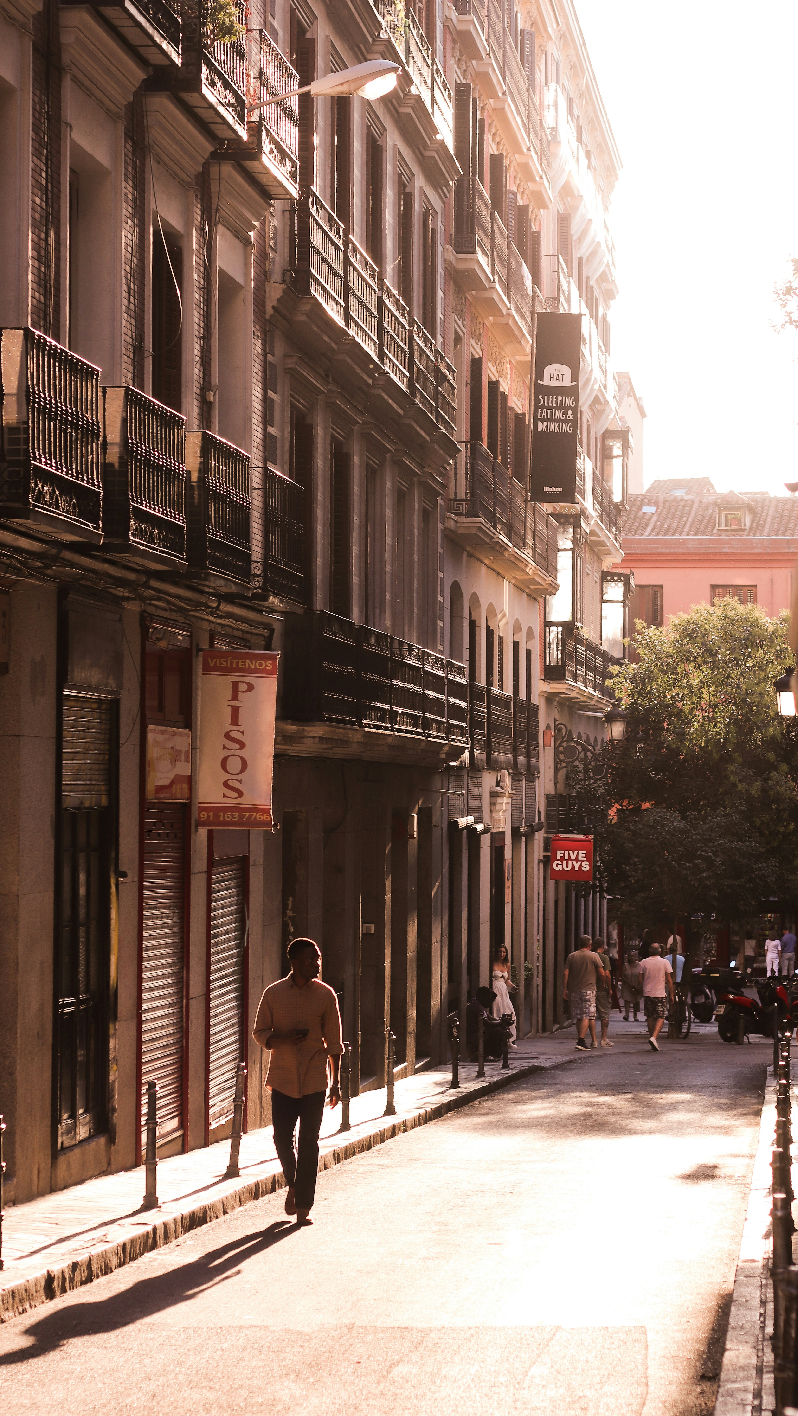 A man walking down a street next to tall buildings
