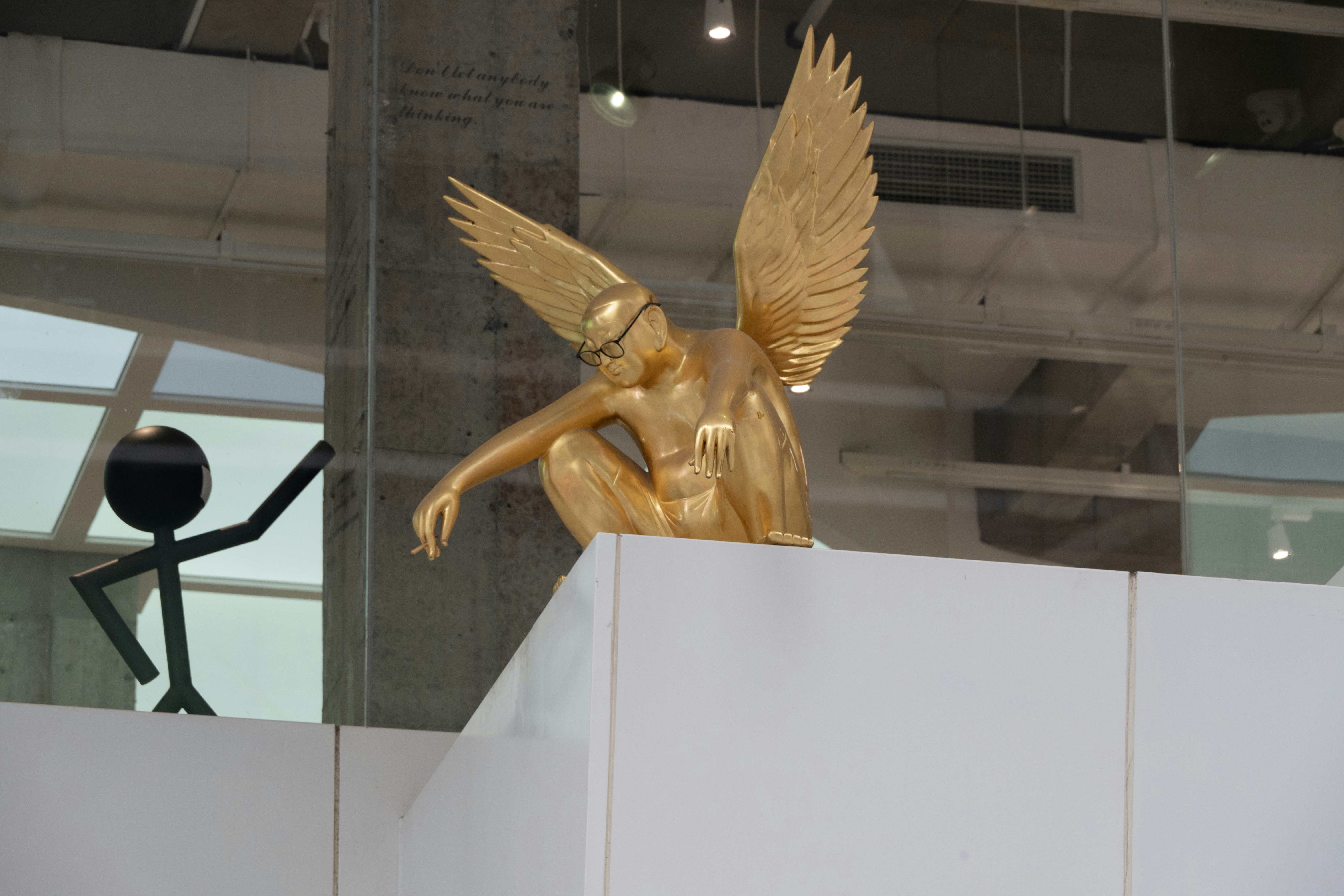 A gold statue of an angel sitting on top of a white box