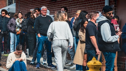 A group of people standing on a sidewalk next to a yellow fire hydrant